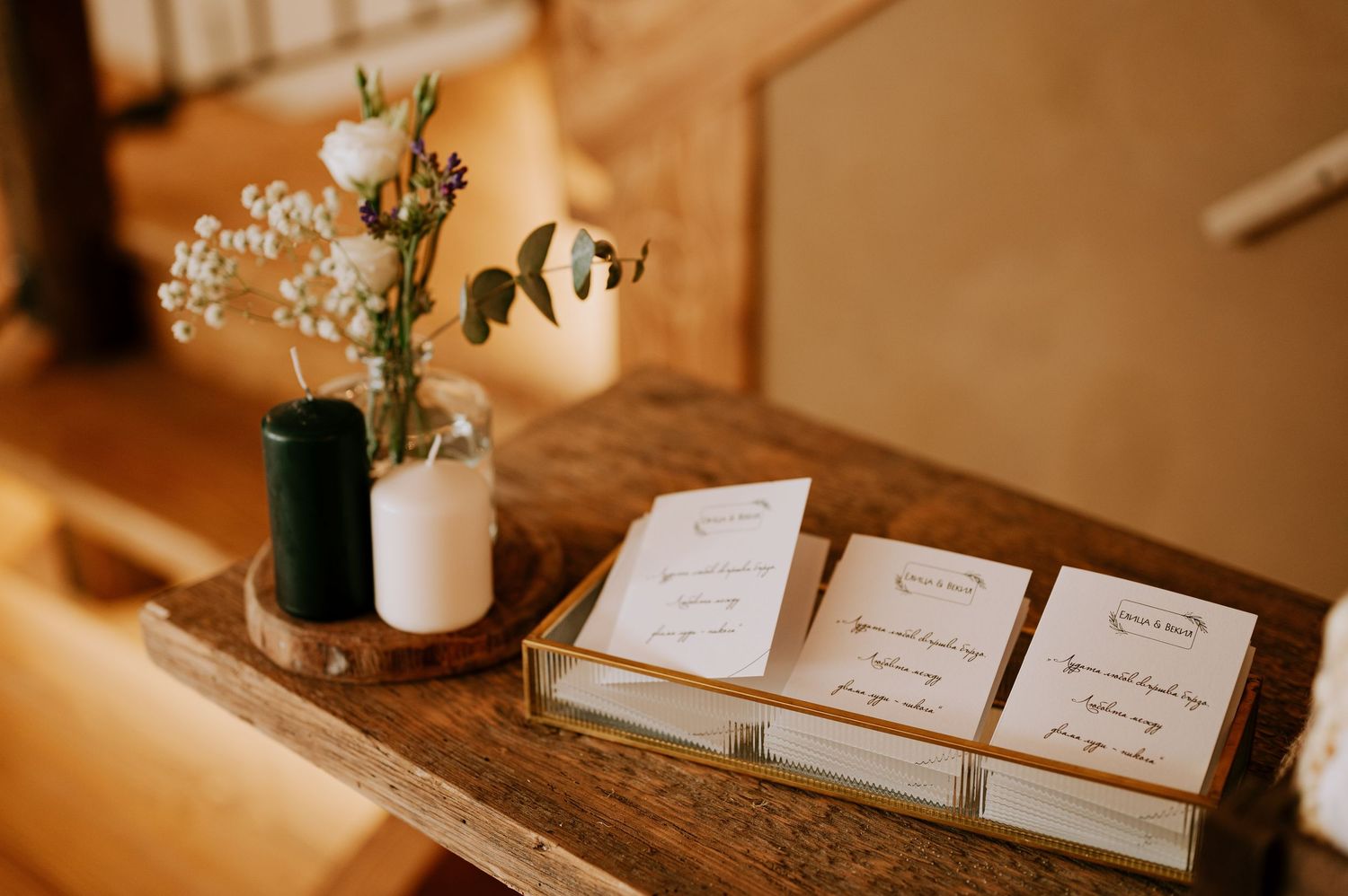 Wedding ceremony programs displayed on a rustic wooden table with delicate floral arrangements in vases.