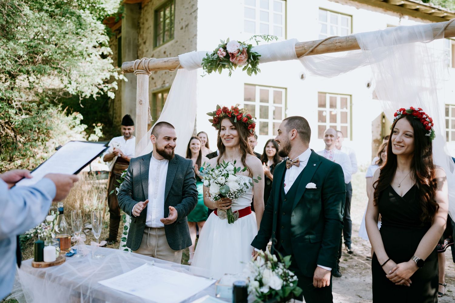 Wedding guests socialize during outdoor reception near rustic venue.
