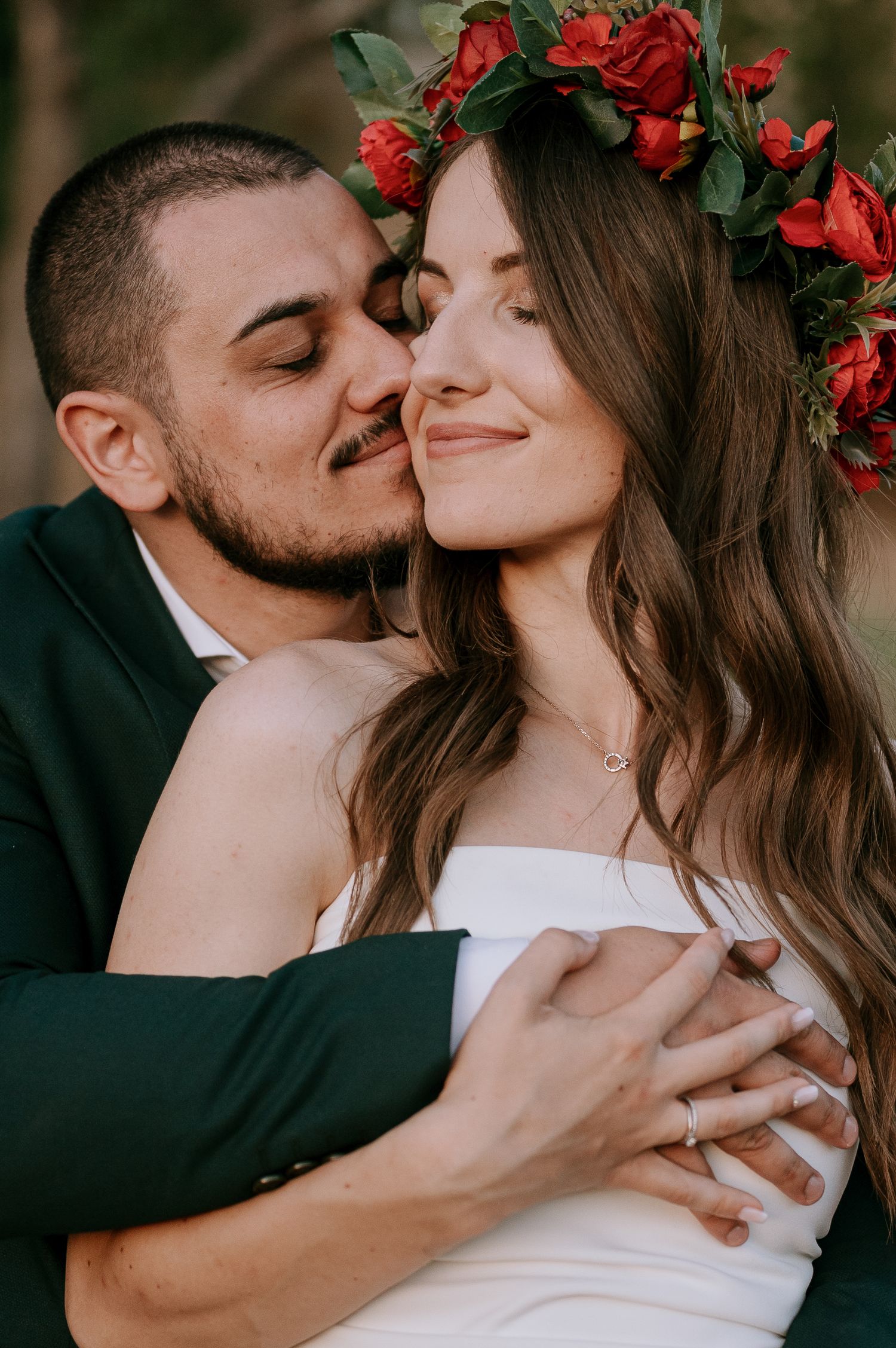 Romantic wedding portraits showing gentle embraces and a red flower crown against natural scenery.