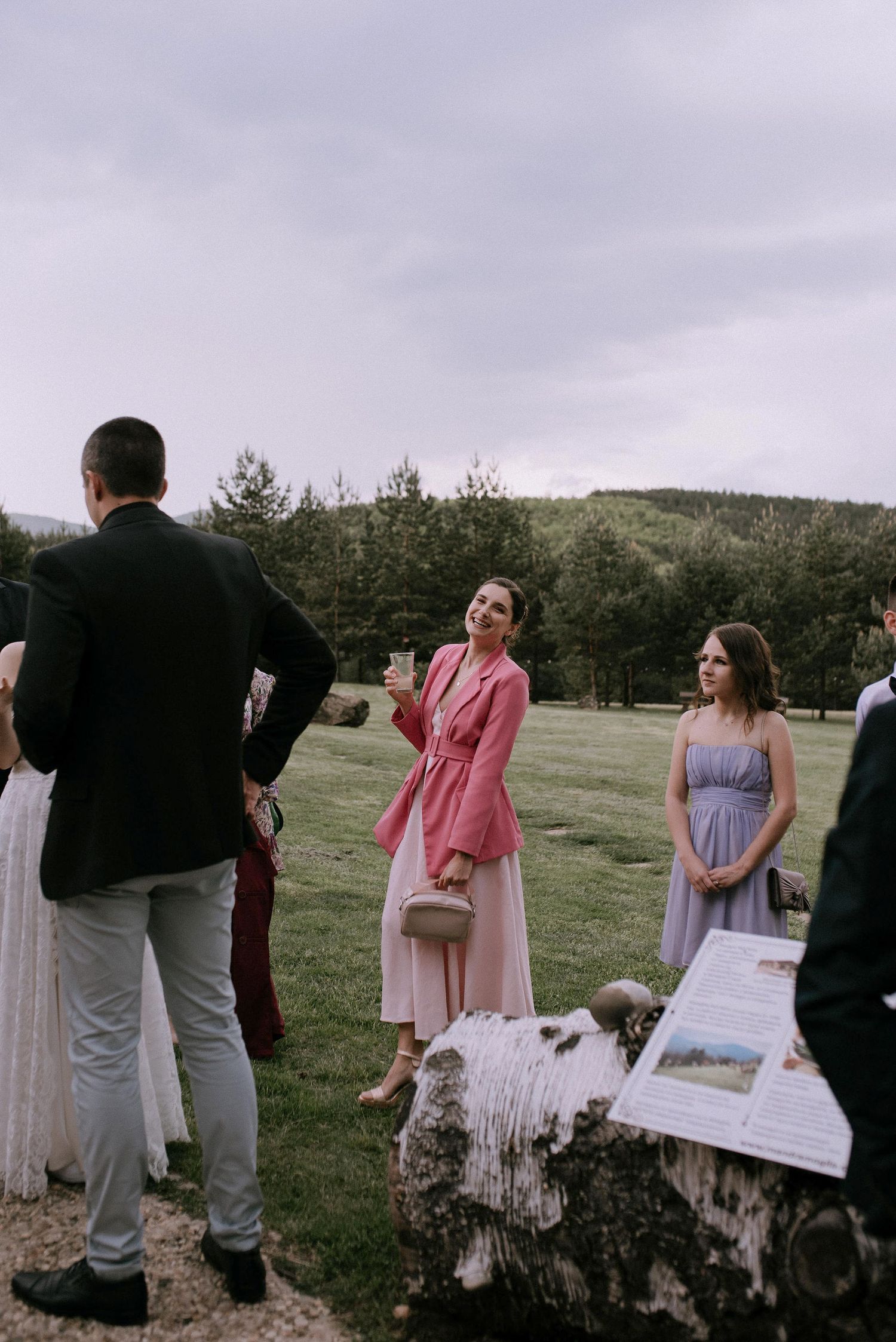 Group of wedding guests standing in a grassy field during an outdoor celebration.
