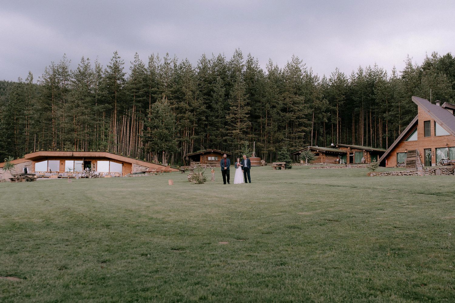 Scenic panorama of an outdoor event space with pine forest and rustic lodges.