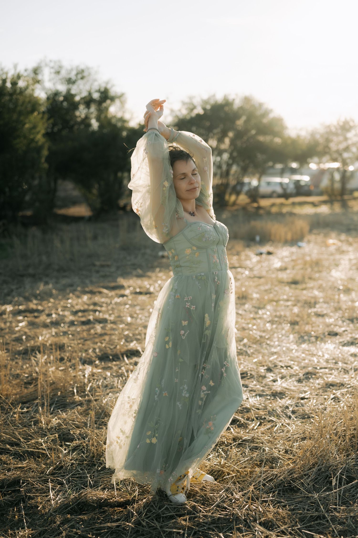 A flowing mint green dress catches the golden light in a dreamy outdoor setting at sunset.