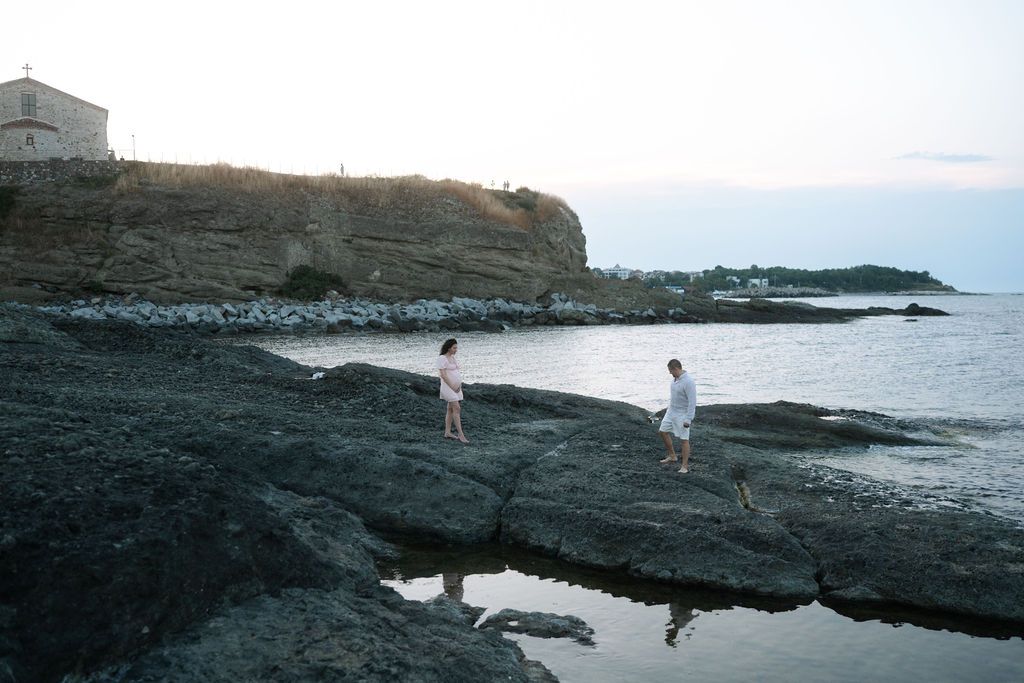 People explore the rugged volcanic coastline during sunset at Poipu Beach in Kauai, Hawaii.