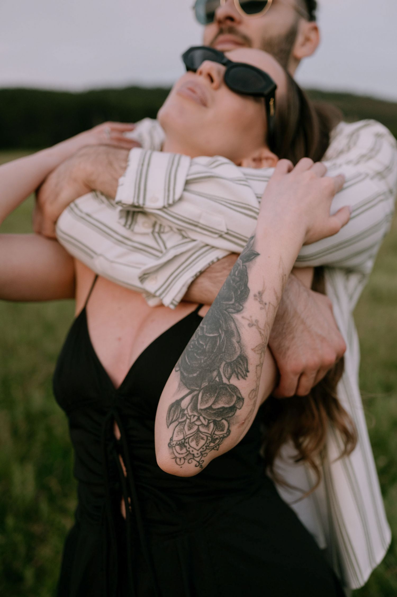 A series of close-up shots showing a detailed arm tattoo while wearing sunglasses and a white shirt outdoors.