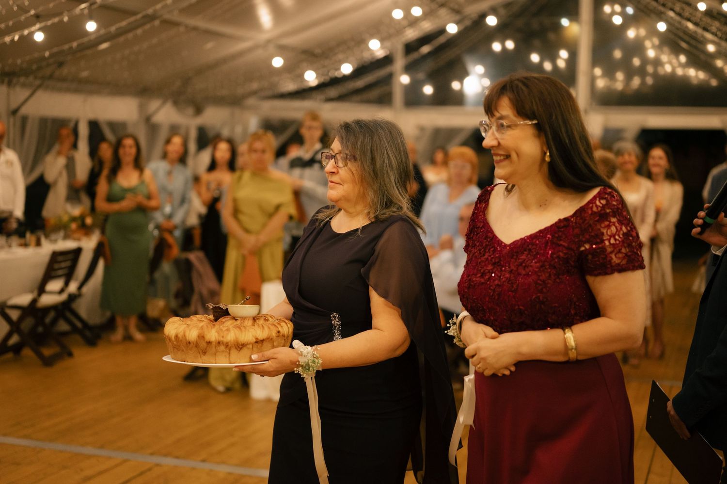 Wedding reception dance floor filled with guests celebrating under warm lighting and string lights.