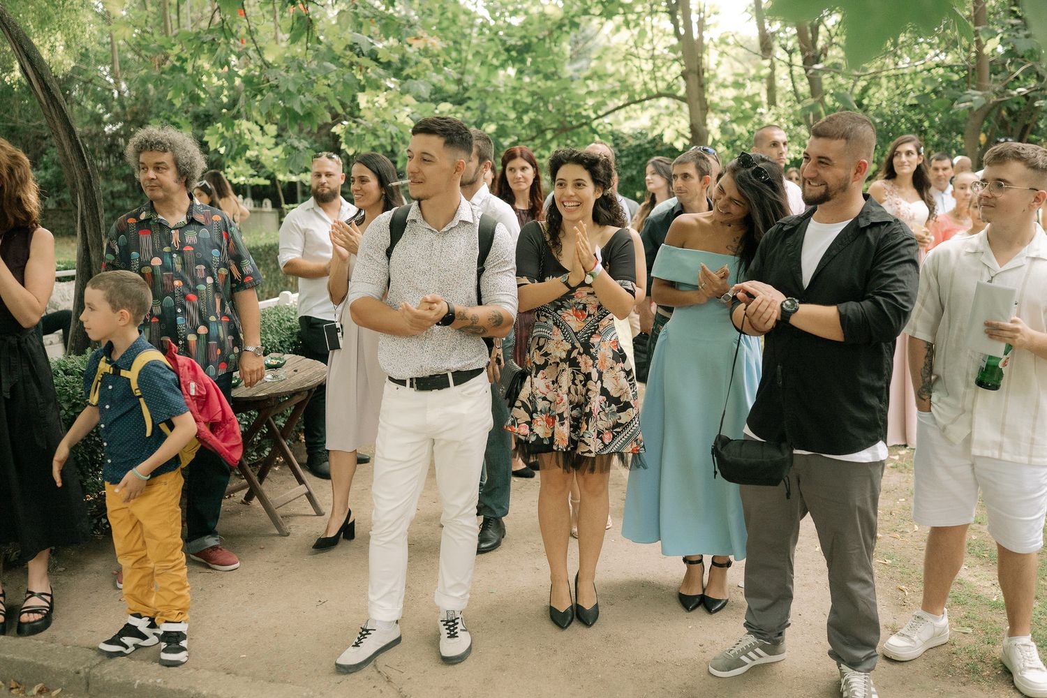 People dancing in a line outdoors at a festive summer gathering in a park setting.