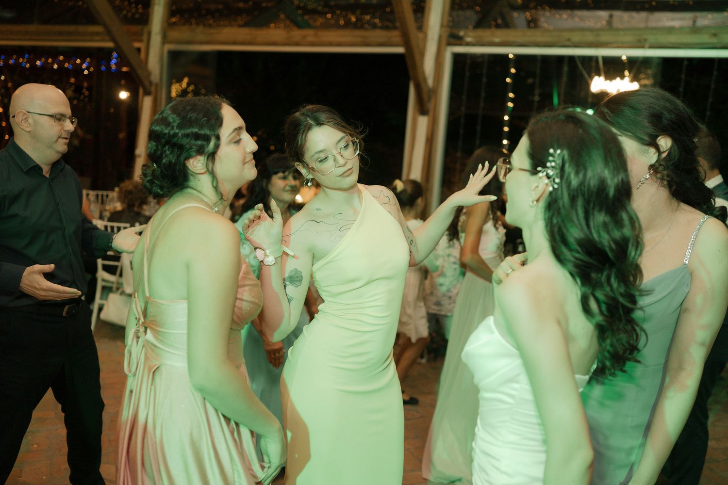 People dancing together at a dimly lit wedding reception with green lighting effects.