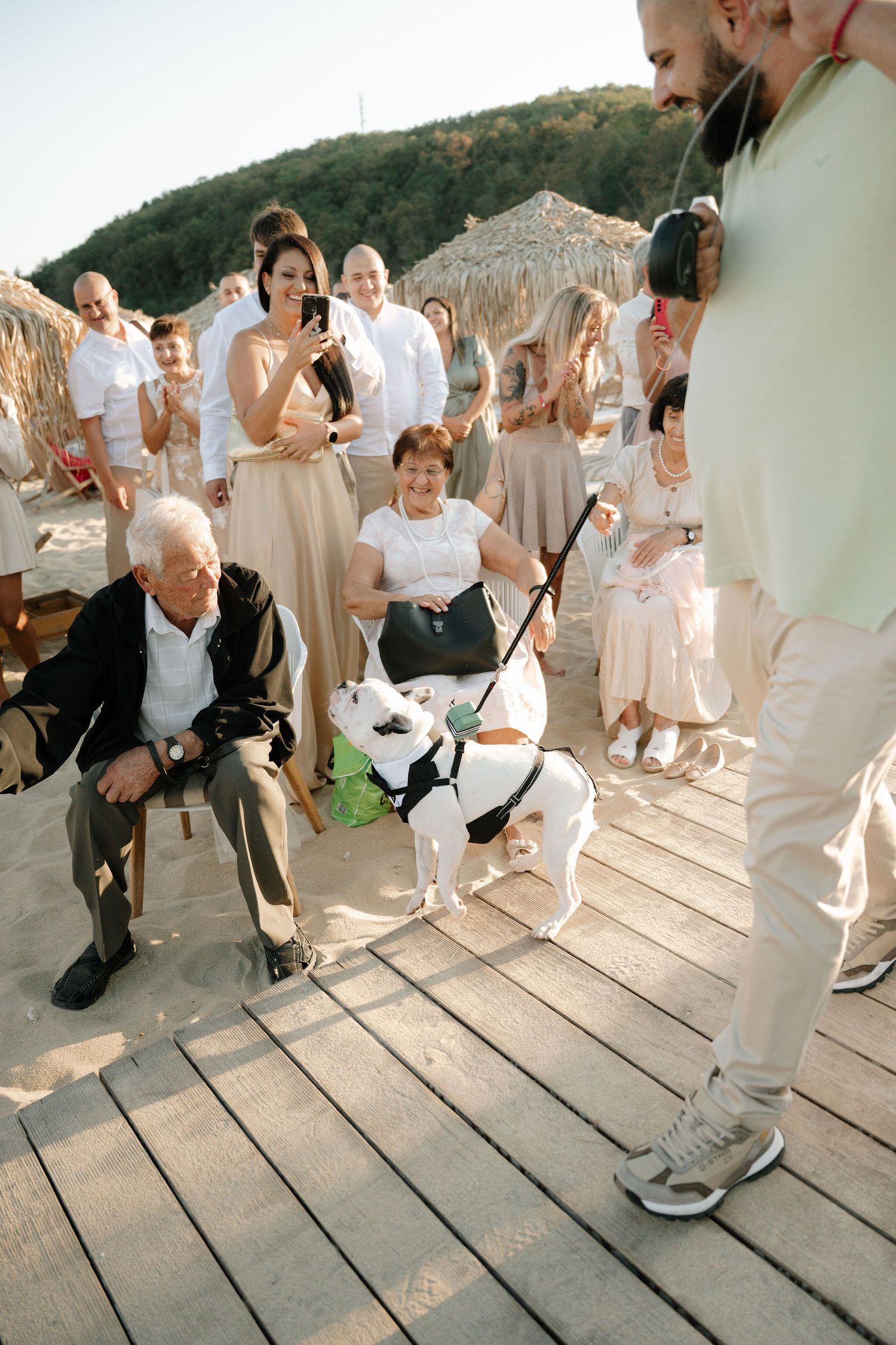 Wedding guests dance and celebrate on a rustic wooden deck during an outdoor reception.