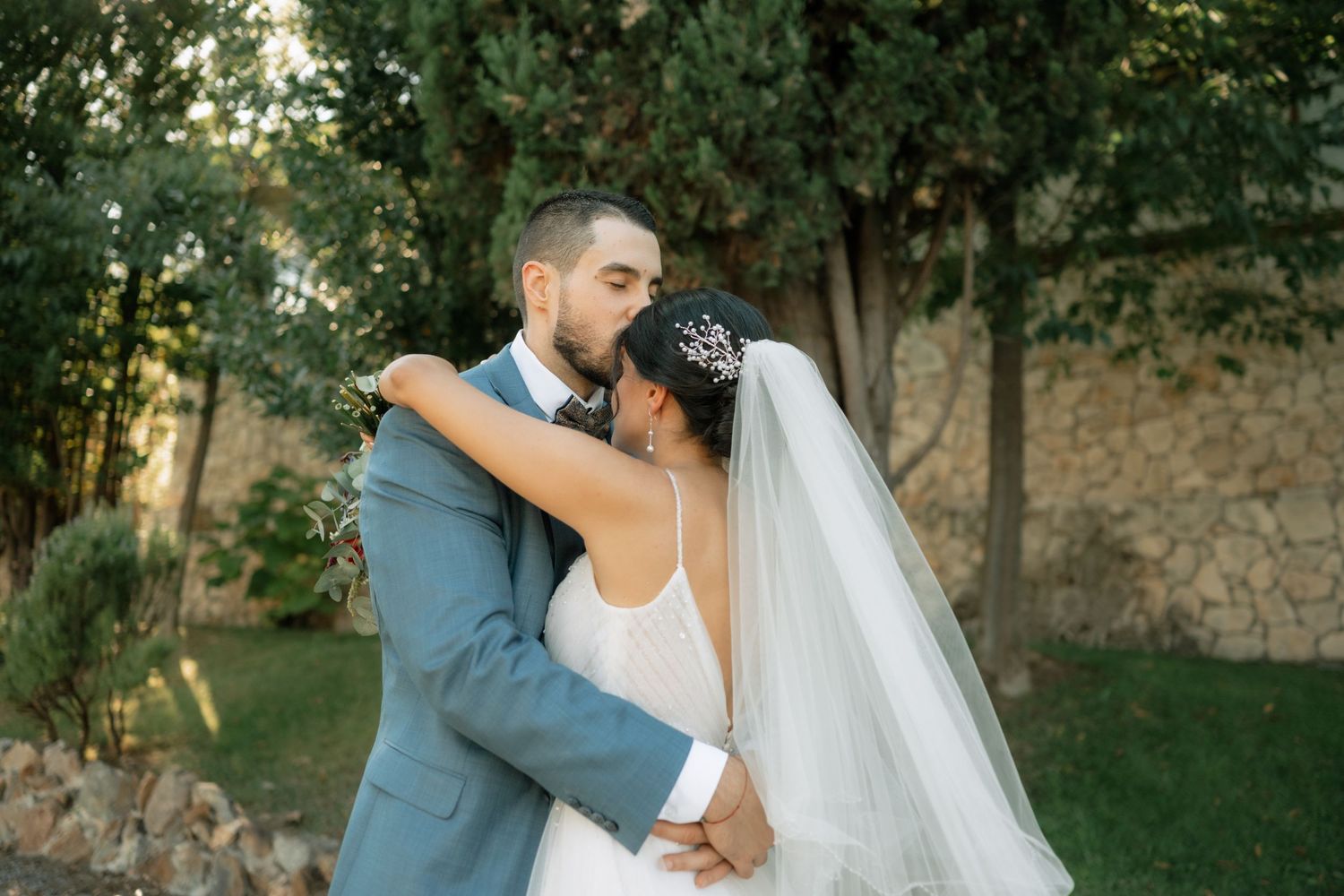 Bride and groom share intimate moments during their outdoor wedding photoshoot in a lush garden setting.