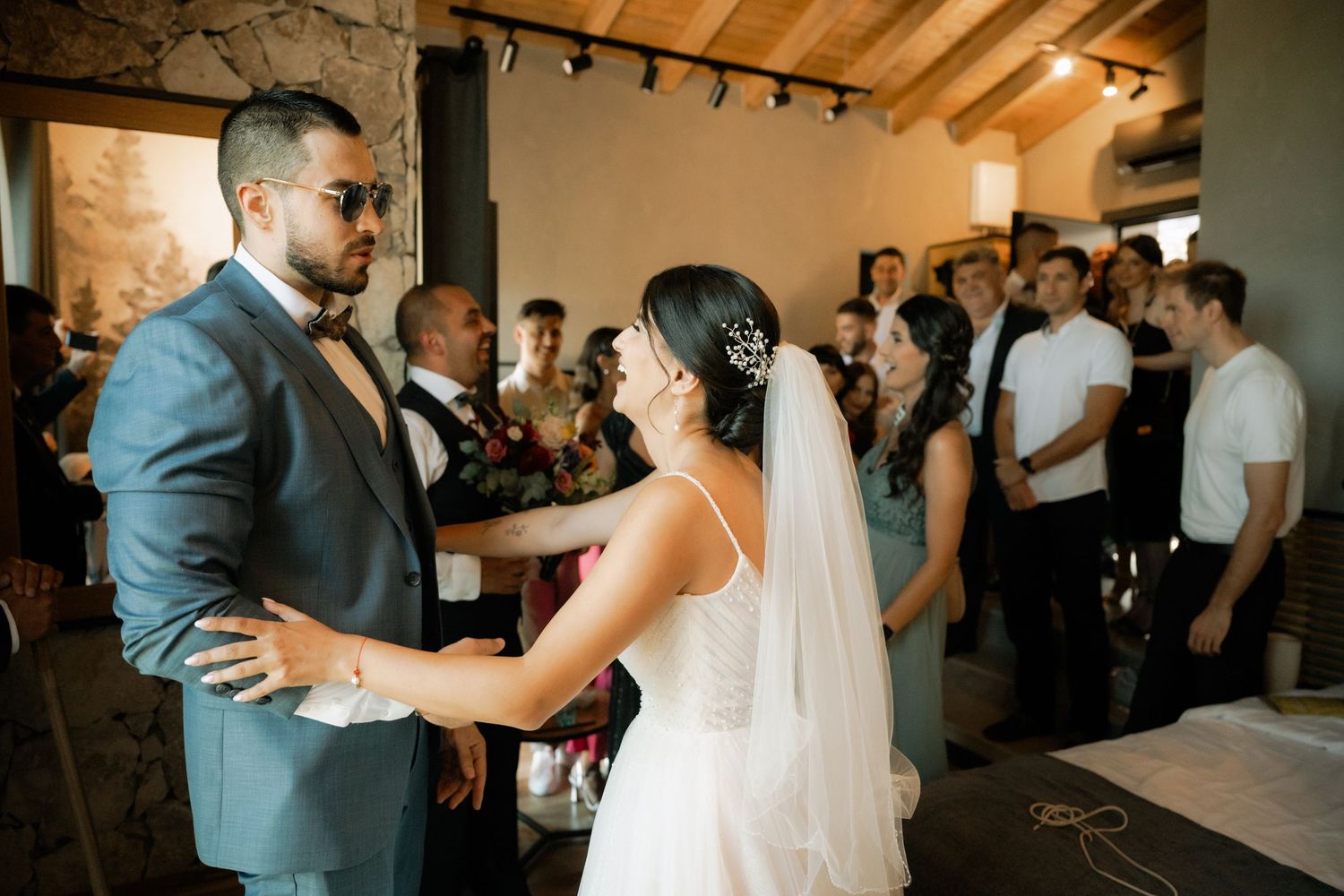 Couple shares romantic dance at wedding reception in rustic venue with wooden beams and warm lighting.