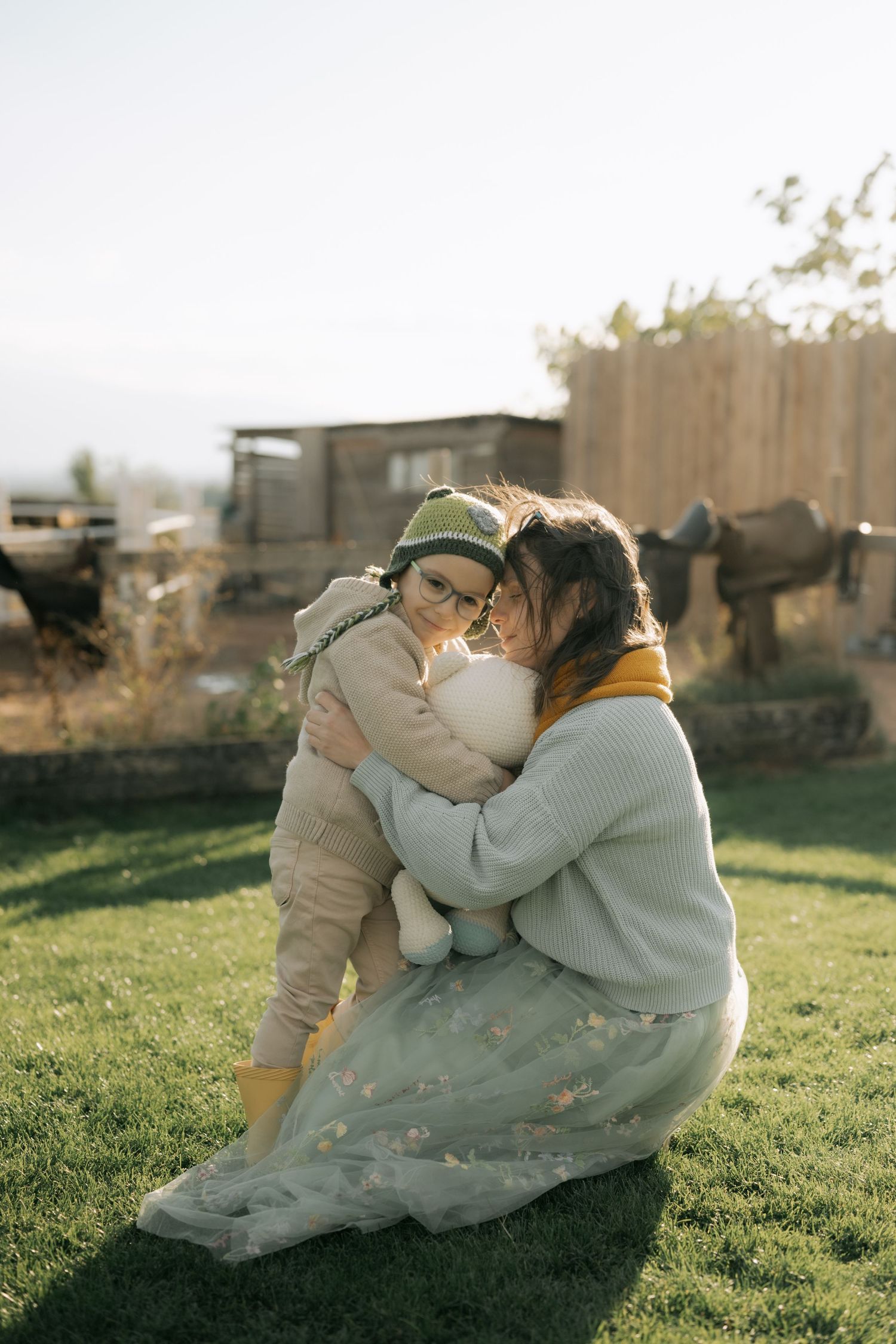 A couple embraces lovingly on a grassy lawn during golden hour, creating a romantic outdoor scene.