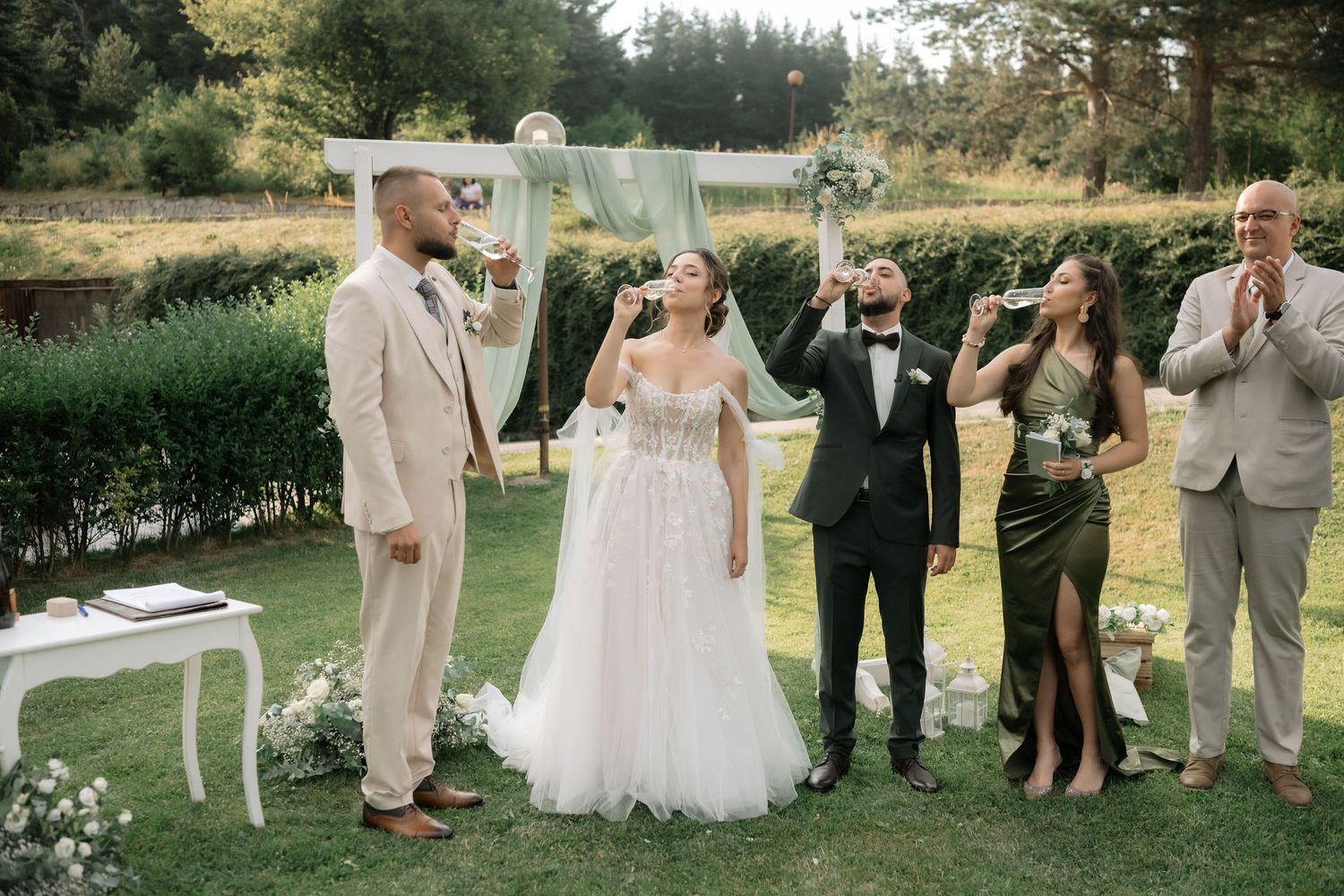 Wedding party gathered outdoors in a garden setting during a summer celebration.