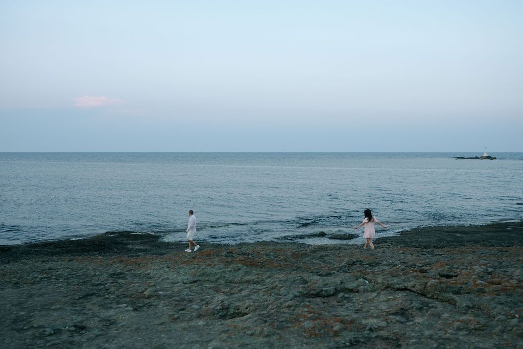 A scenic panoramic view of a tranquil beach shoreline with calm ocean waters stretching to the horizon.