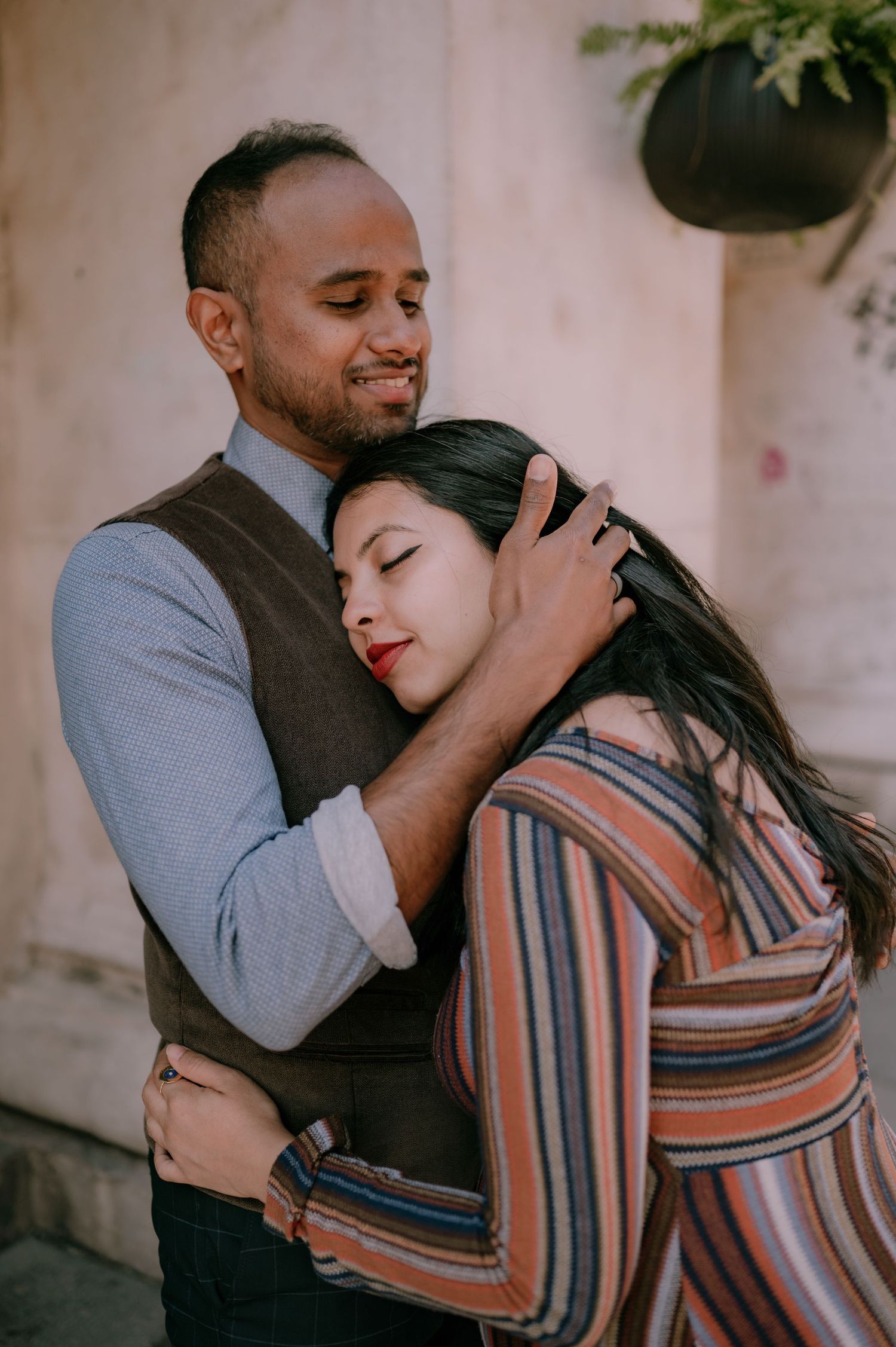 A couple shares a tender embrace, the man gently holding the woman as she rests her head on his chest.