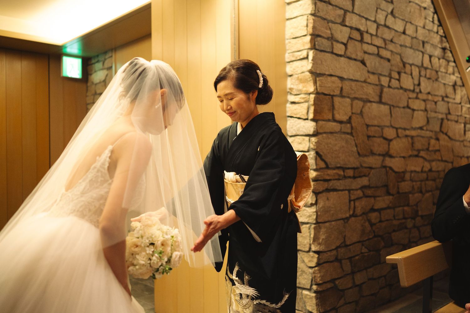 Intimate moment during bridal fitting as dress attendant perfects the wedding gown details.