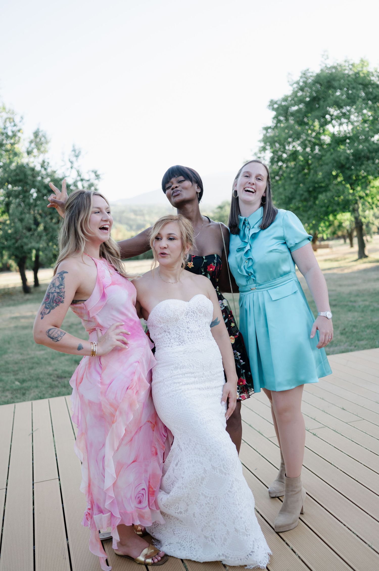 Joyful bridal party sharing laughs on outdoor wooden deck.