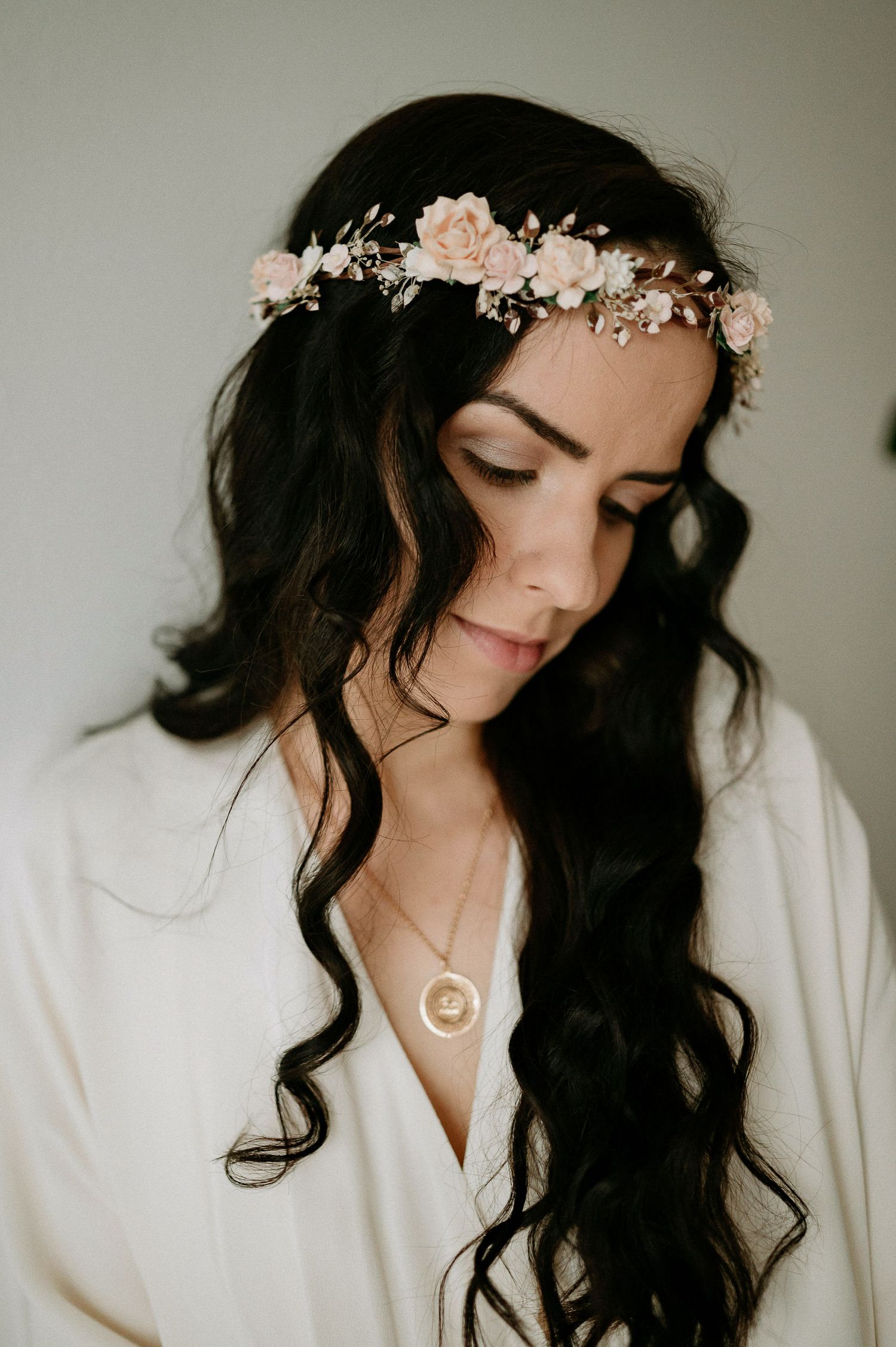 Intimate bridal photo with dark wavy hair, white robe and floral crown.