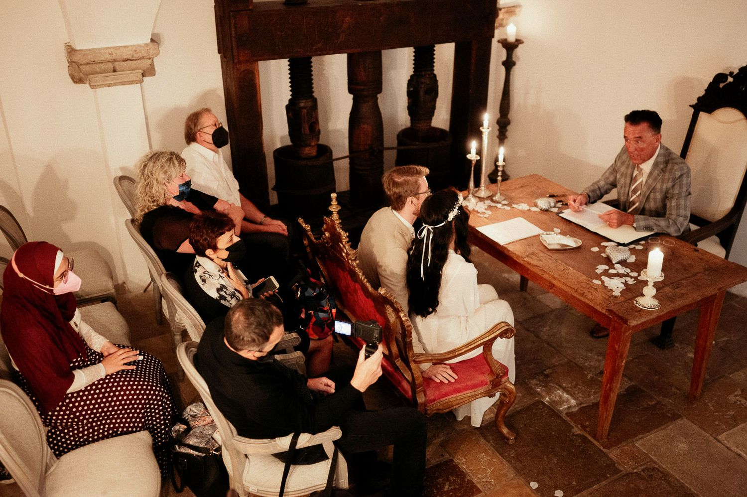 Guests gathered around tables in a dimly lit rustic room with candlelight.