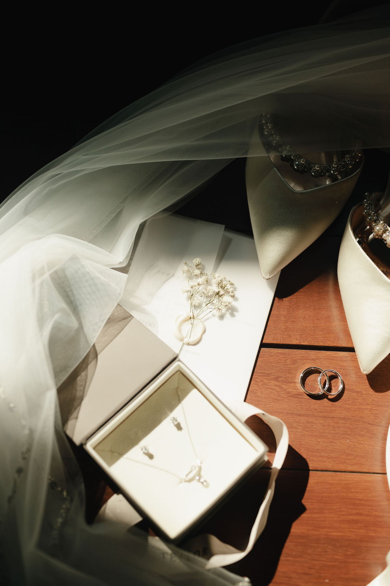 Wedding rings and white fabric arranged artistically on wooden surface.