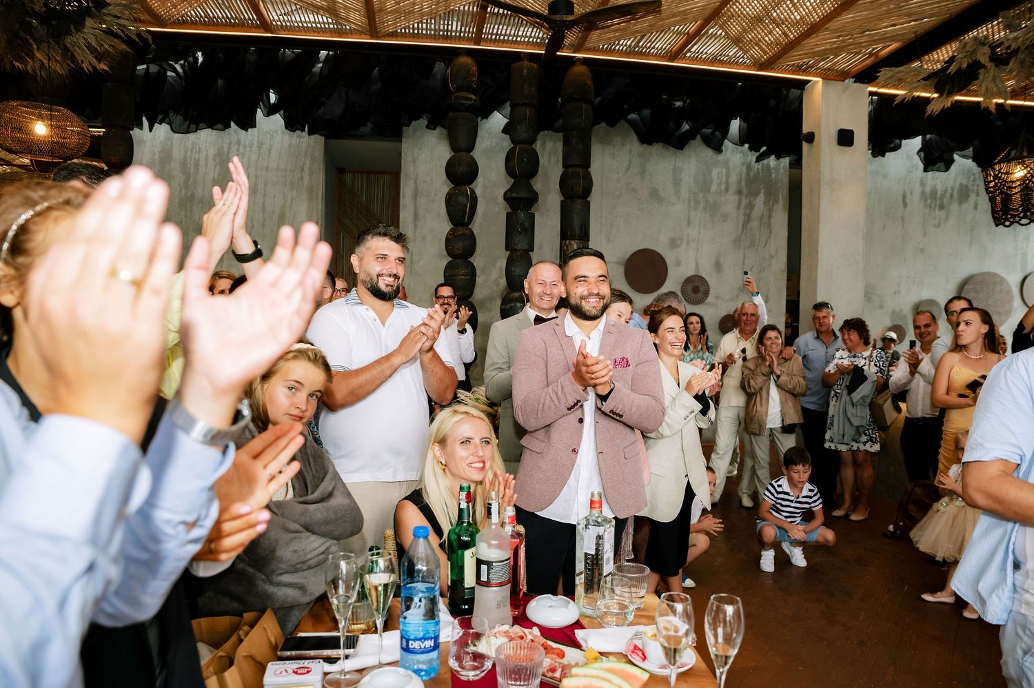 Wedding reception candid moments with guests celebrating in dimly lit venue space.