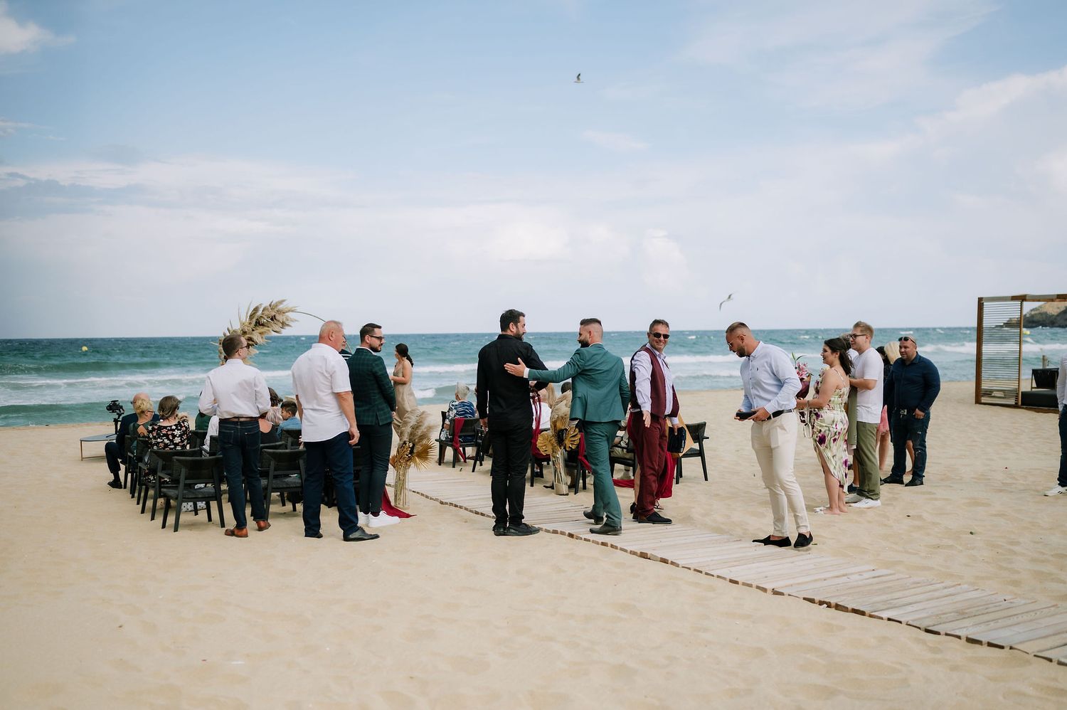 Panoramic view of wedding guests gathered along a beachfront.