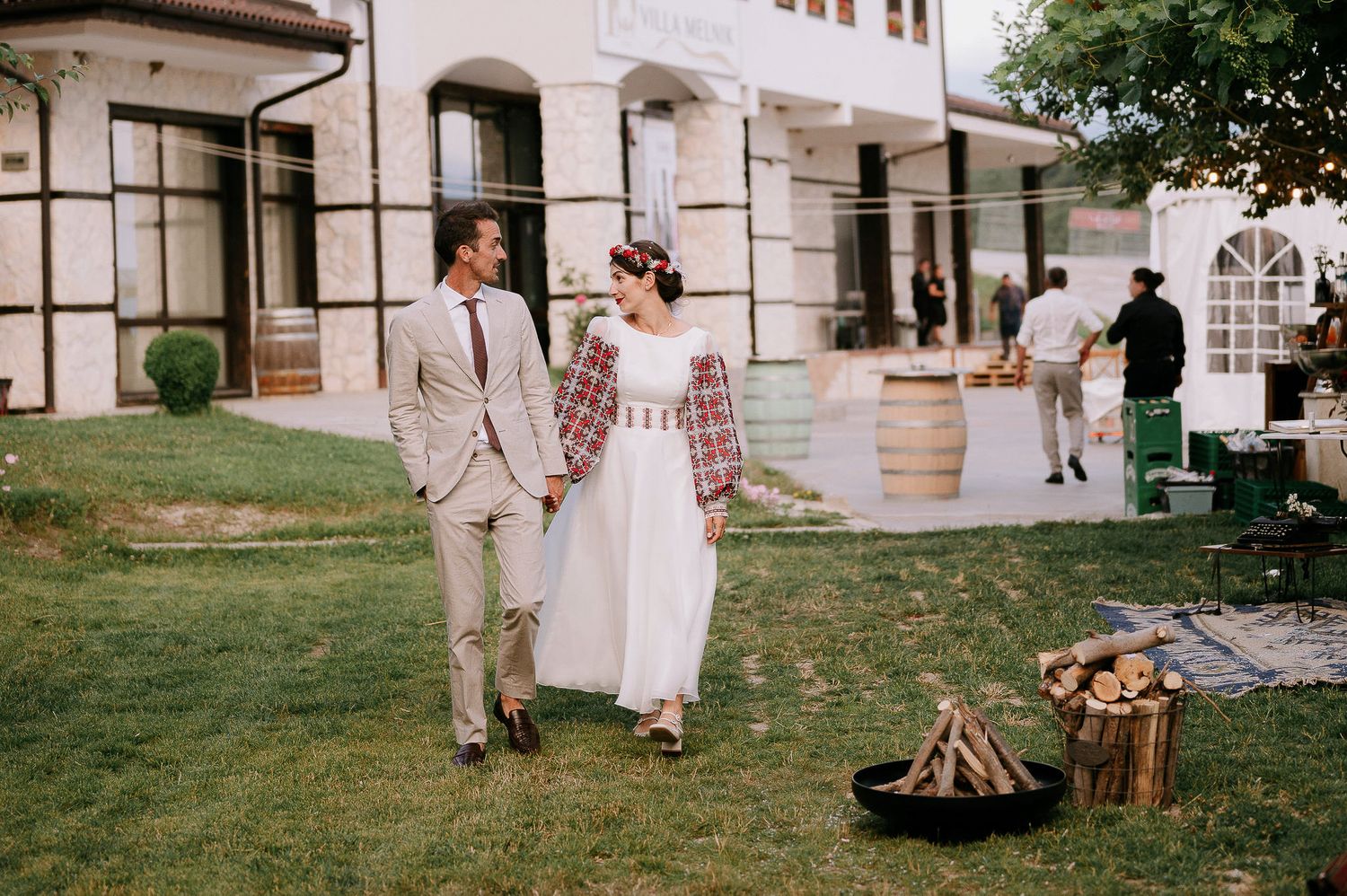 Elegant outdoor event setup near a white building with a bonfire and rustic decor.