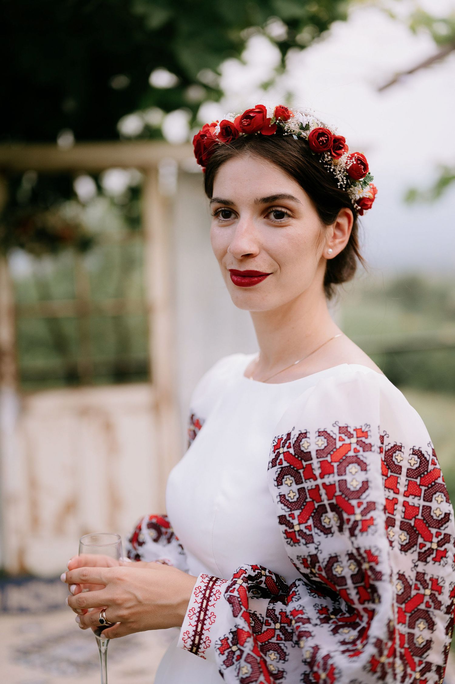 Portrait series showing red rose crown and white dress with traditional red embroidered details.