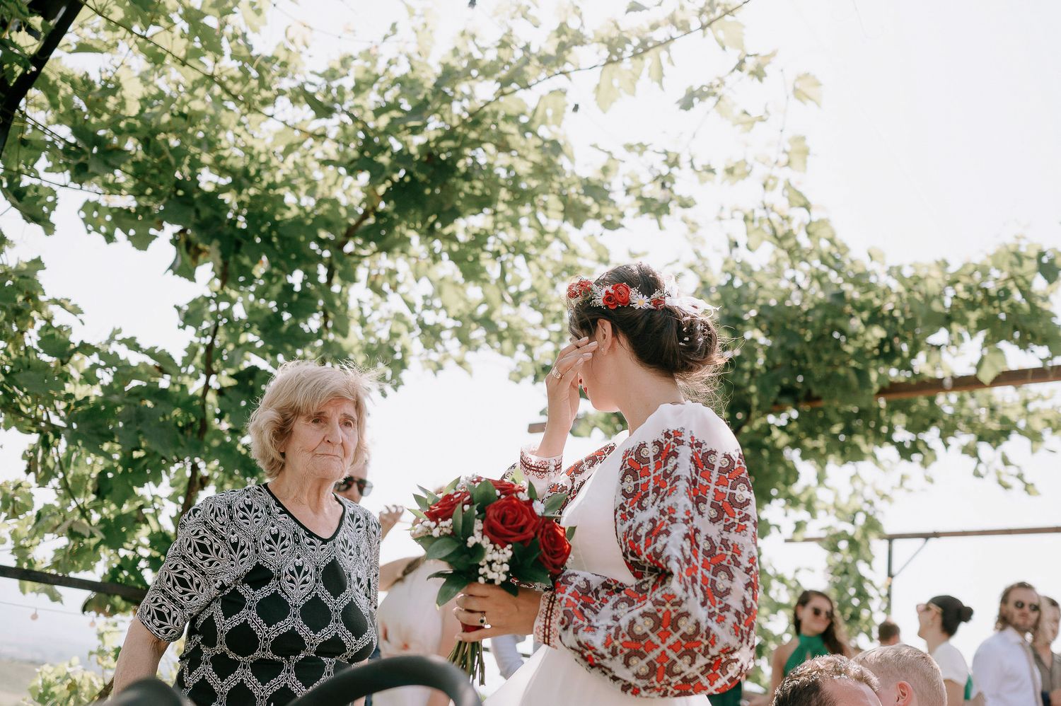 Wedding guests celebrating outdoors beneath leafy green trees.