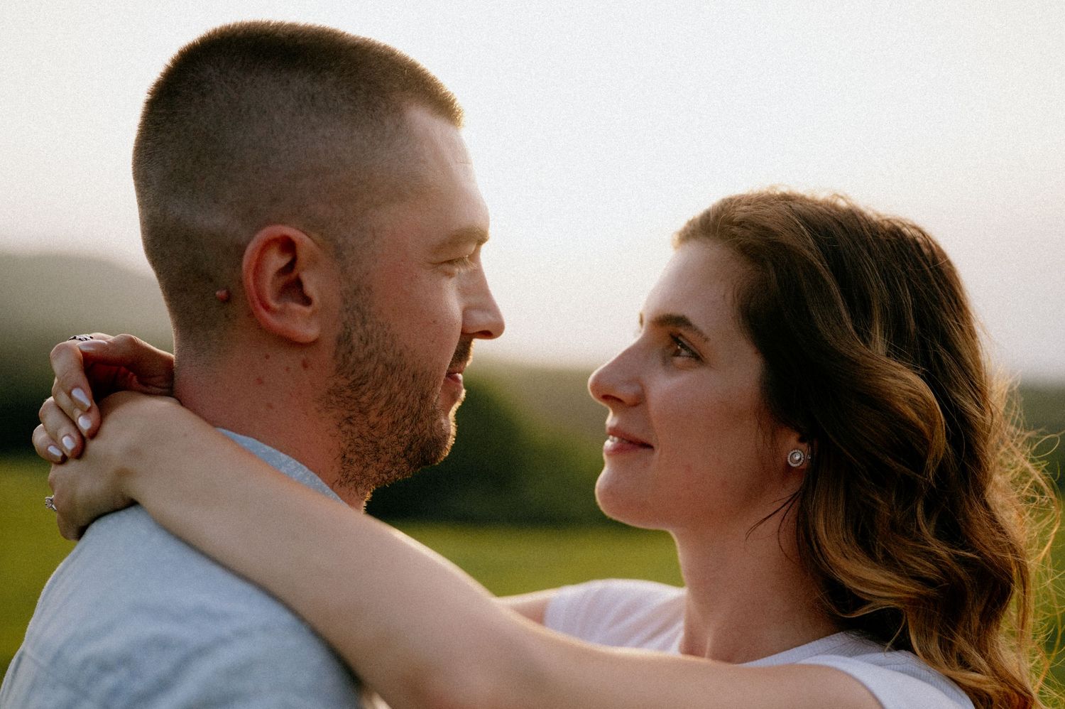 Romantic couple portrait with rolling hills in background during sunset.