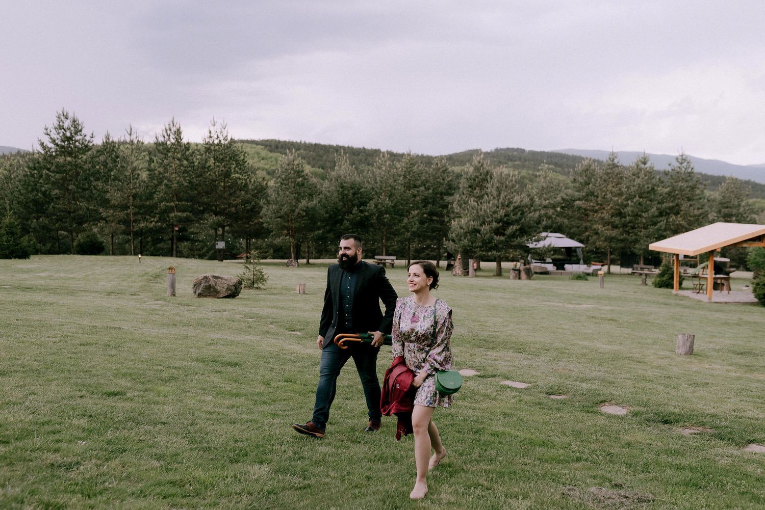 Outdoor wedding ceremony setup with wooden benches and mountain views in a grassy field.