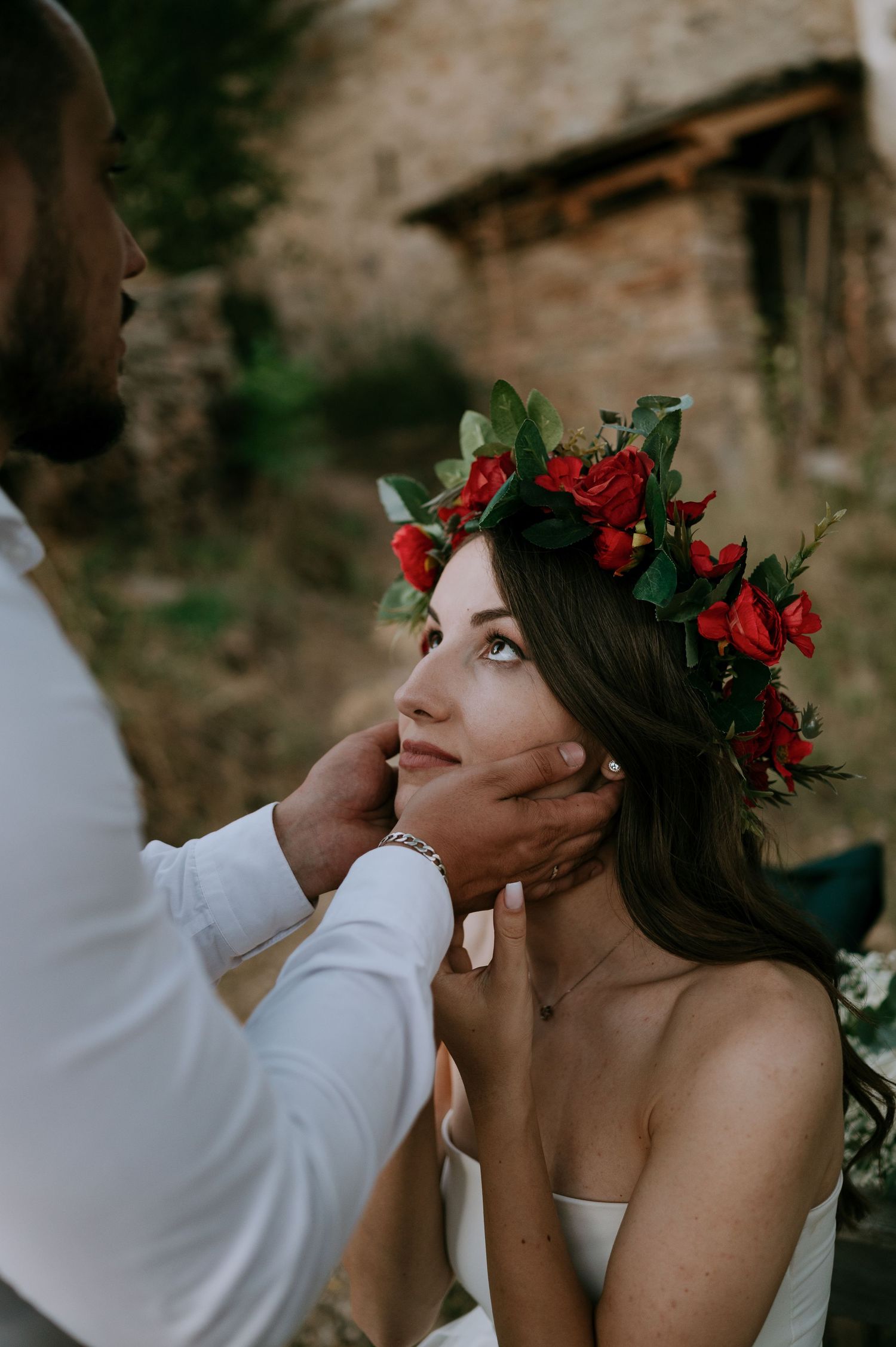 Close-up shot of a bride wearing a red flower crown during an intimate moment.