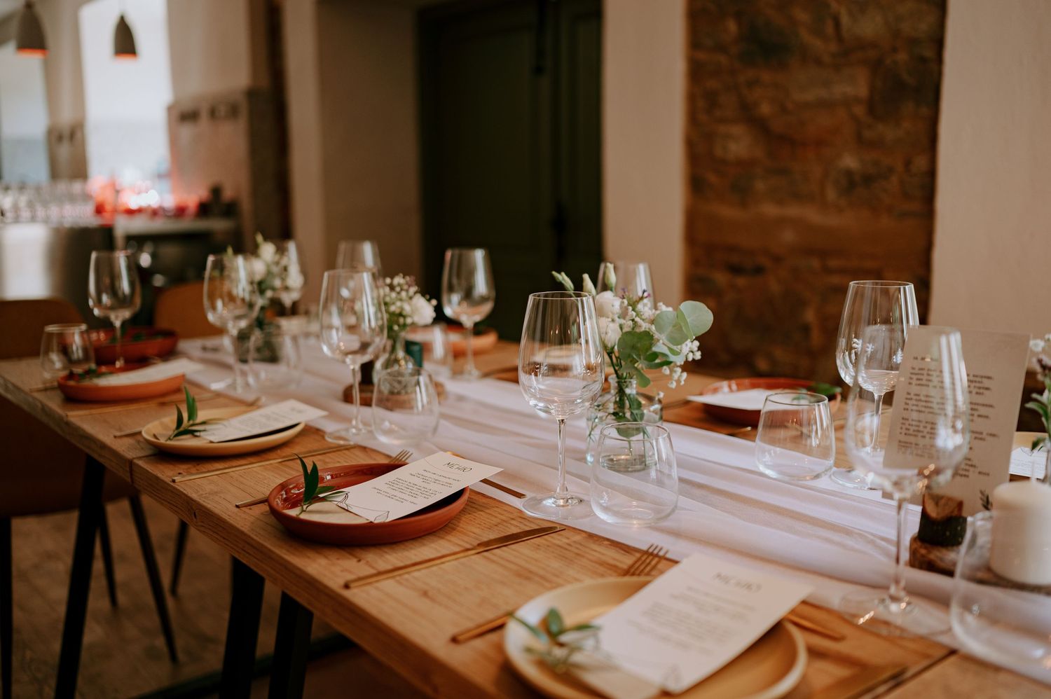 Elegant table settings with wine glasses and place cards in a rustic dining room.