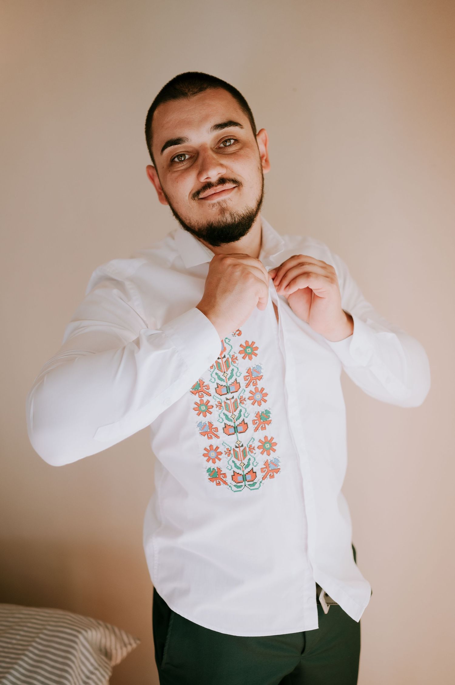 Person wearing white embroidered shirt with floral folk design.