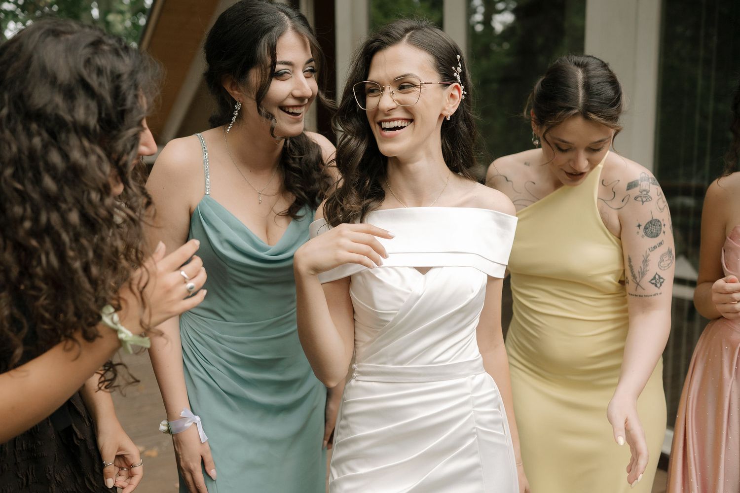 Bridesmaids in pastel colored dresses share joyful moments during a wedding celebration.