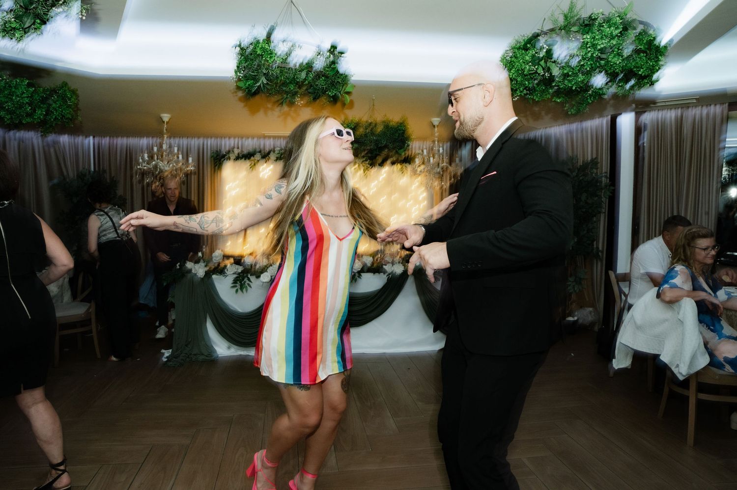 Dancers perform energetic swing dance moves in a dimly lit venue during a lively dance party.