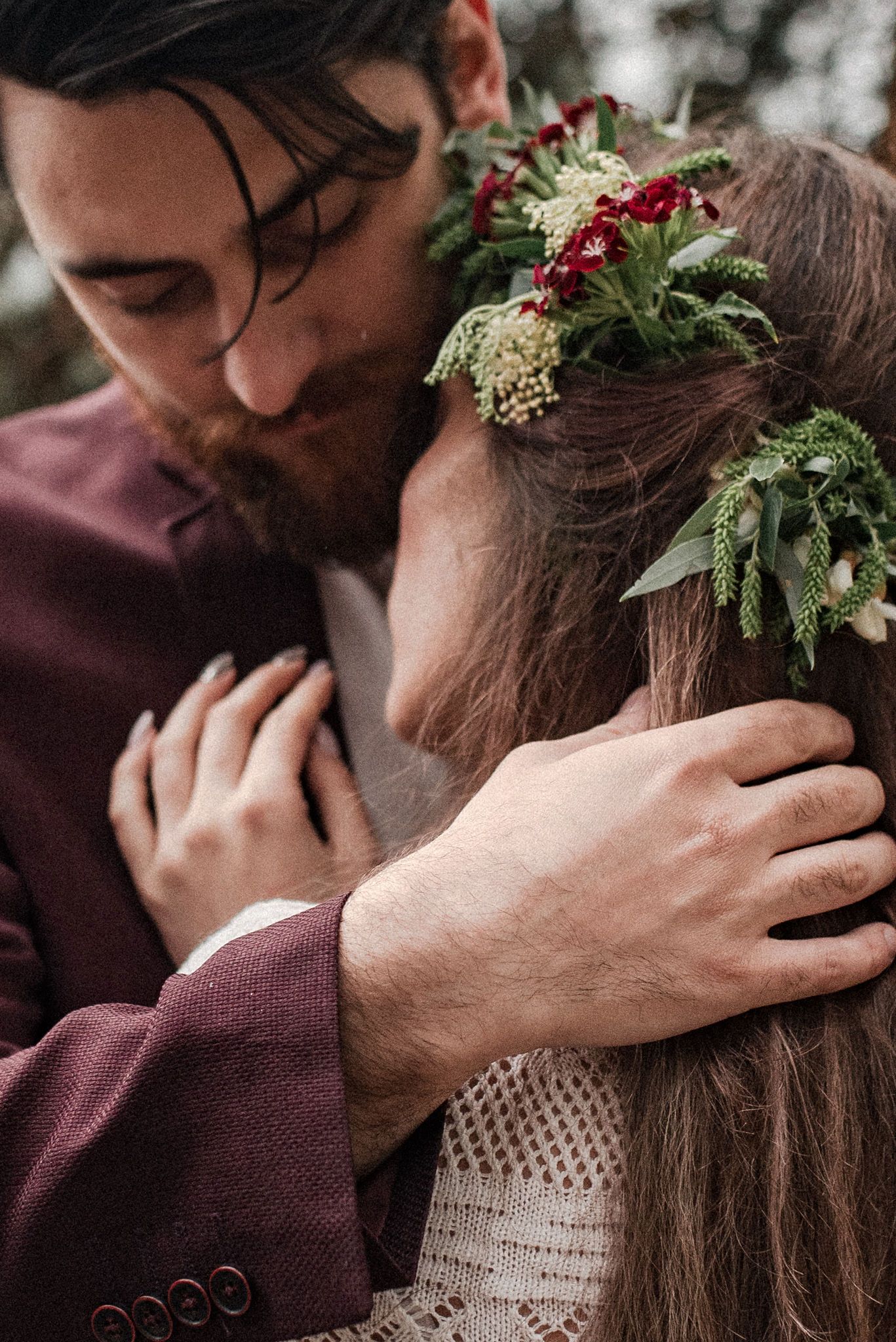 A romantic moment captured in a series of intimate close-up photos with burgundy attire and floral hair accessories.