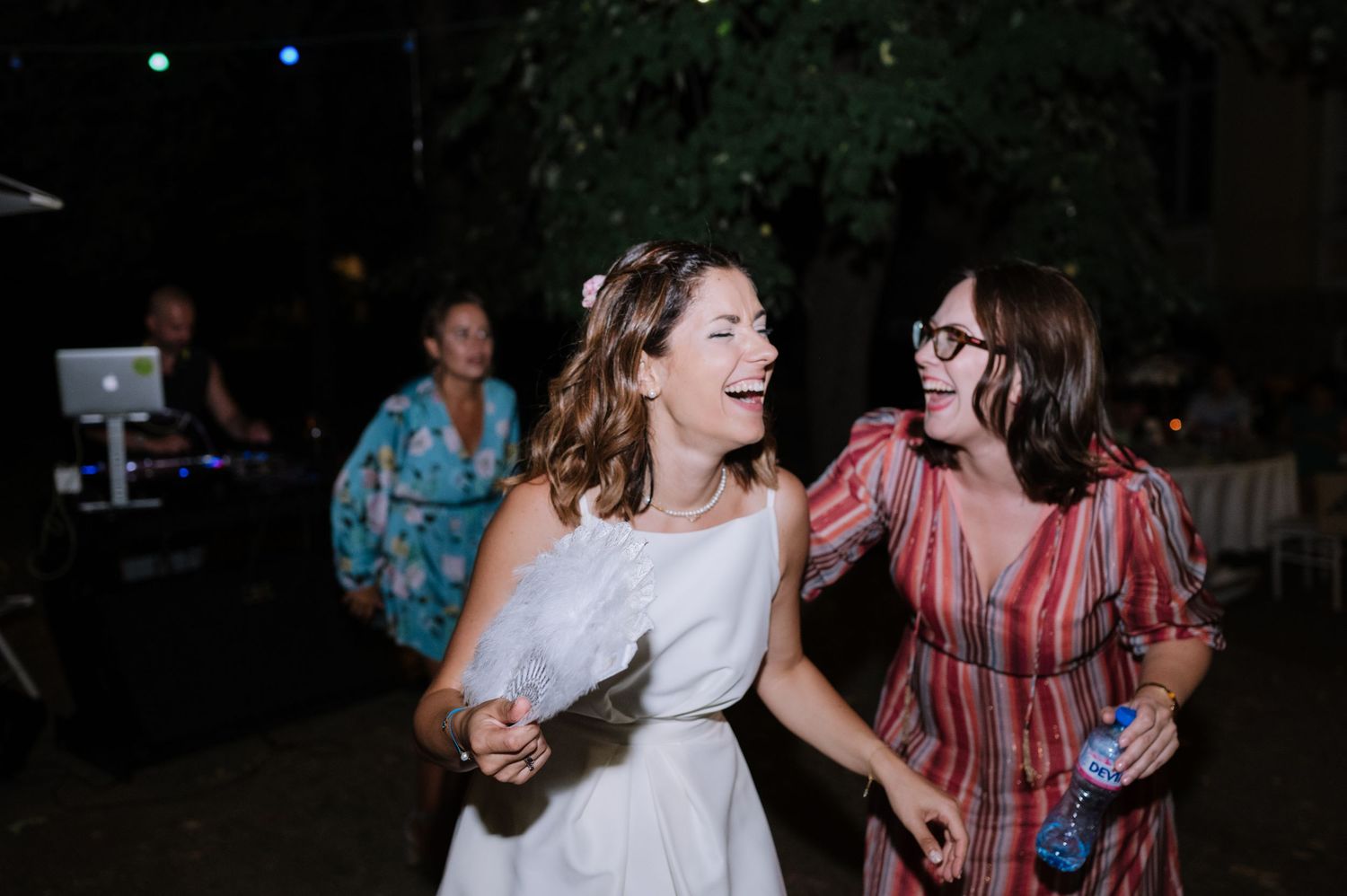 A group of people dance and celebrate together at a nighttime outdoor party or gathering.