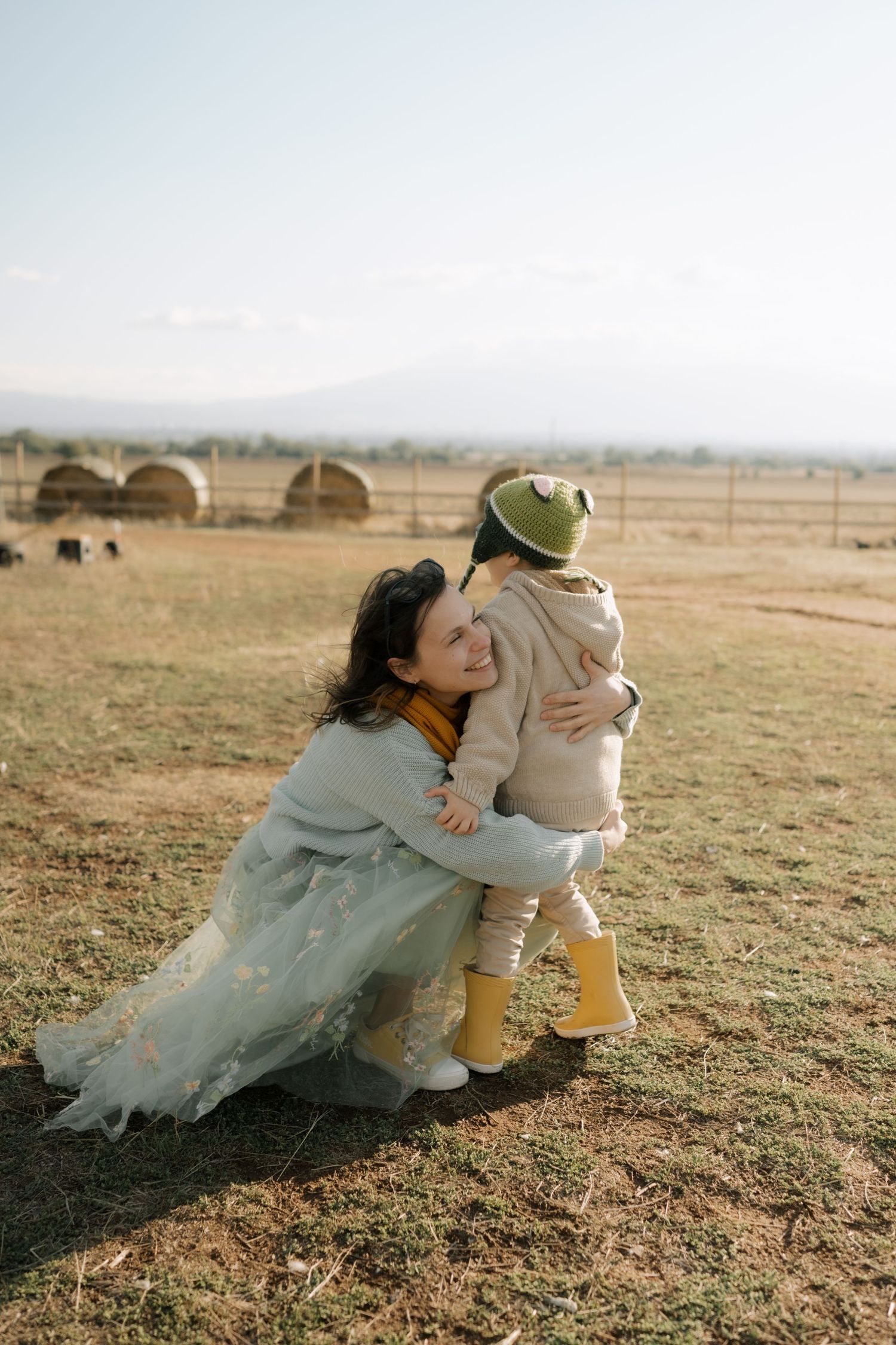 A tender moment shared between two people in a field with mountains in the background on a sunny day.