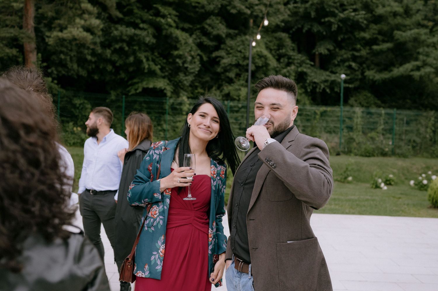 A group of people gather outdoors on a sunny day in a park-like setting.