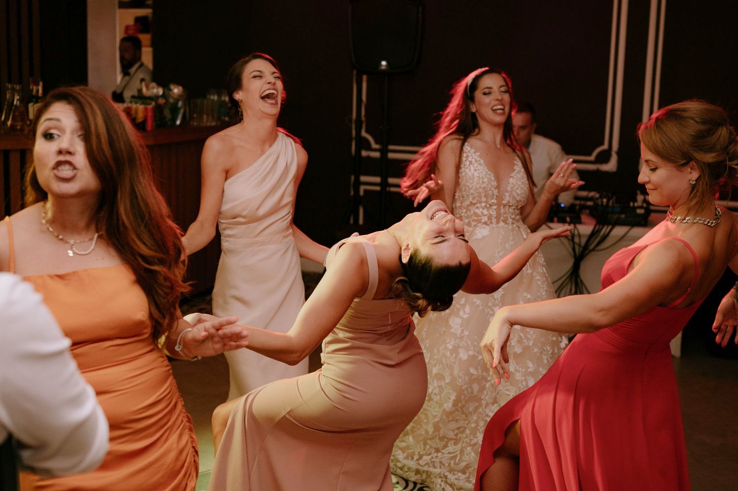 Wedding guests dance joyfully under string lights at an outdoor evening celebration.