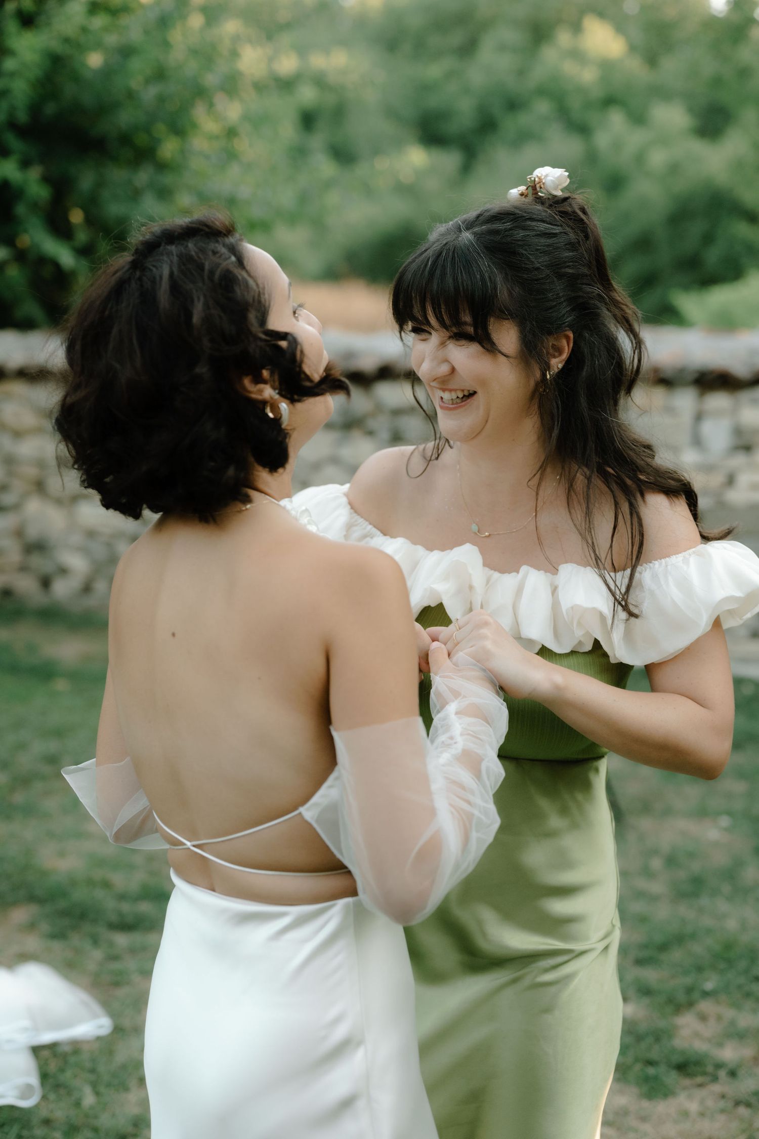 Two people in wedding attire share a tender moment while dancing together outdoors in a garden setting.