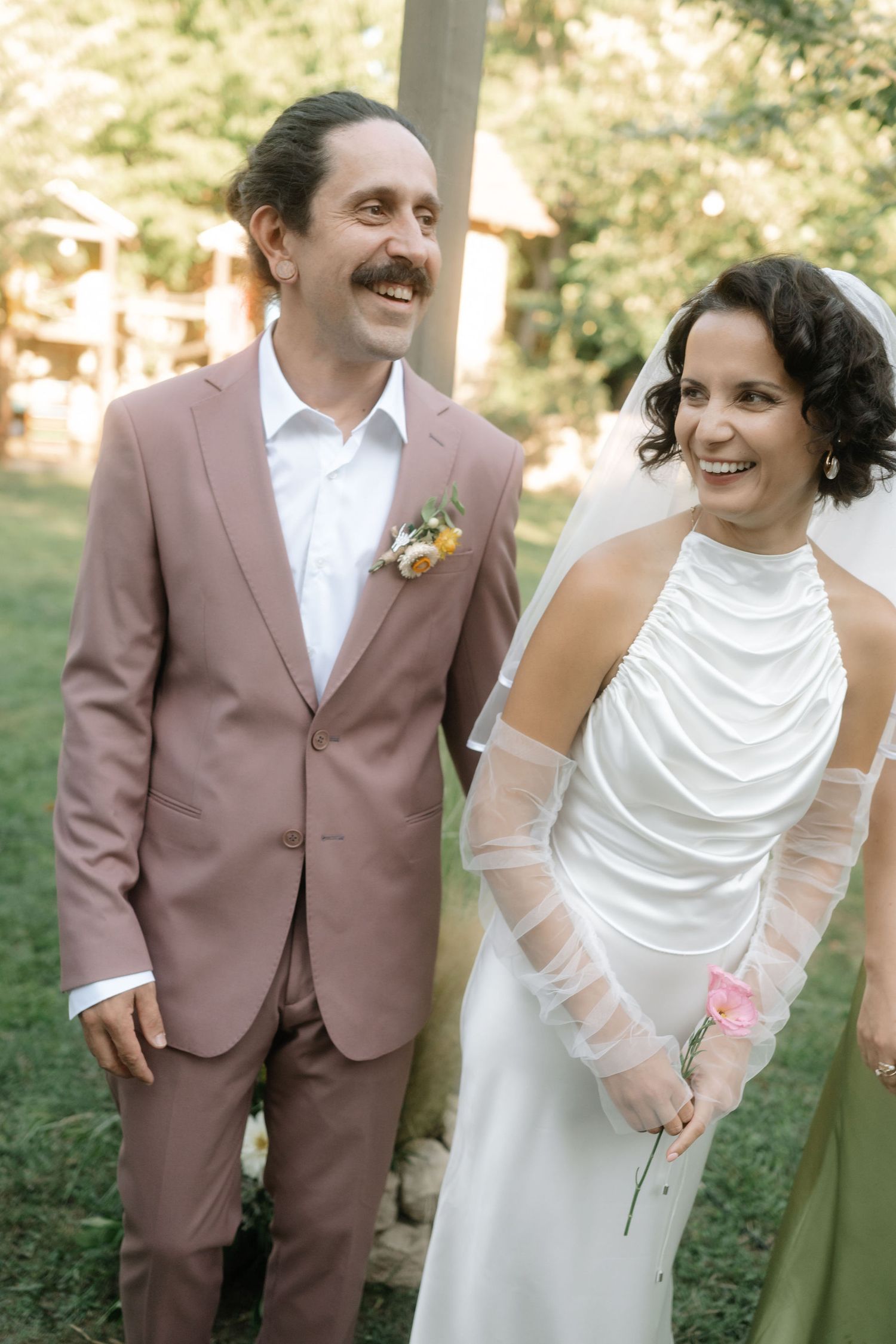 A joyful wedding couple shares candid laughing moments in a series of outdoor photos wearing brown suit and white dress.