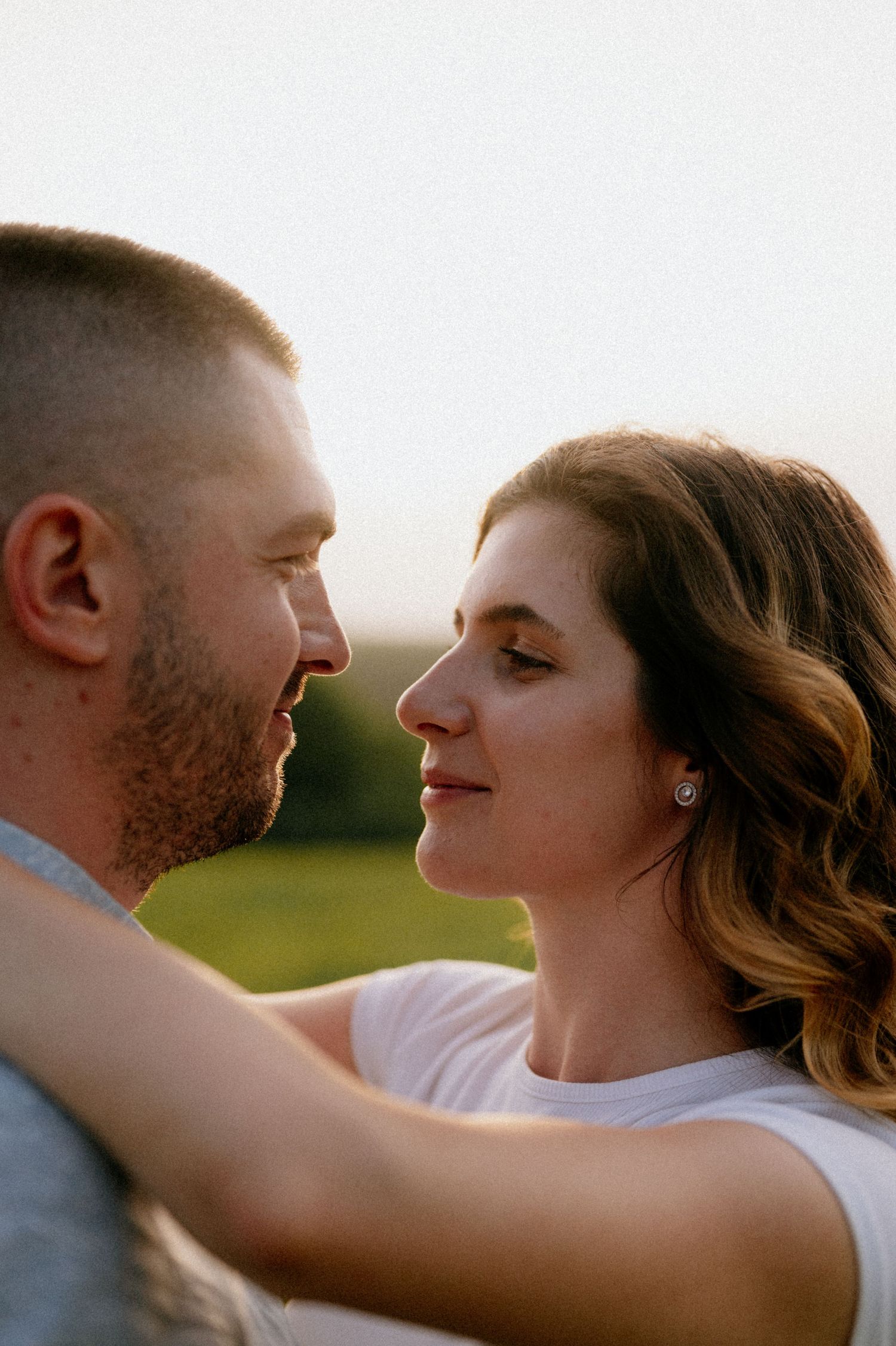 Side profile of couple in intimate embrace during outdoor photo session.