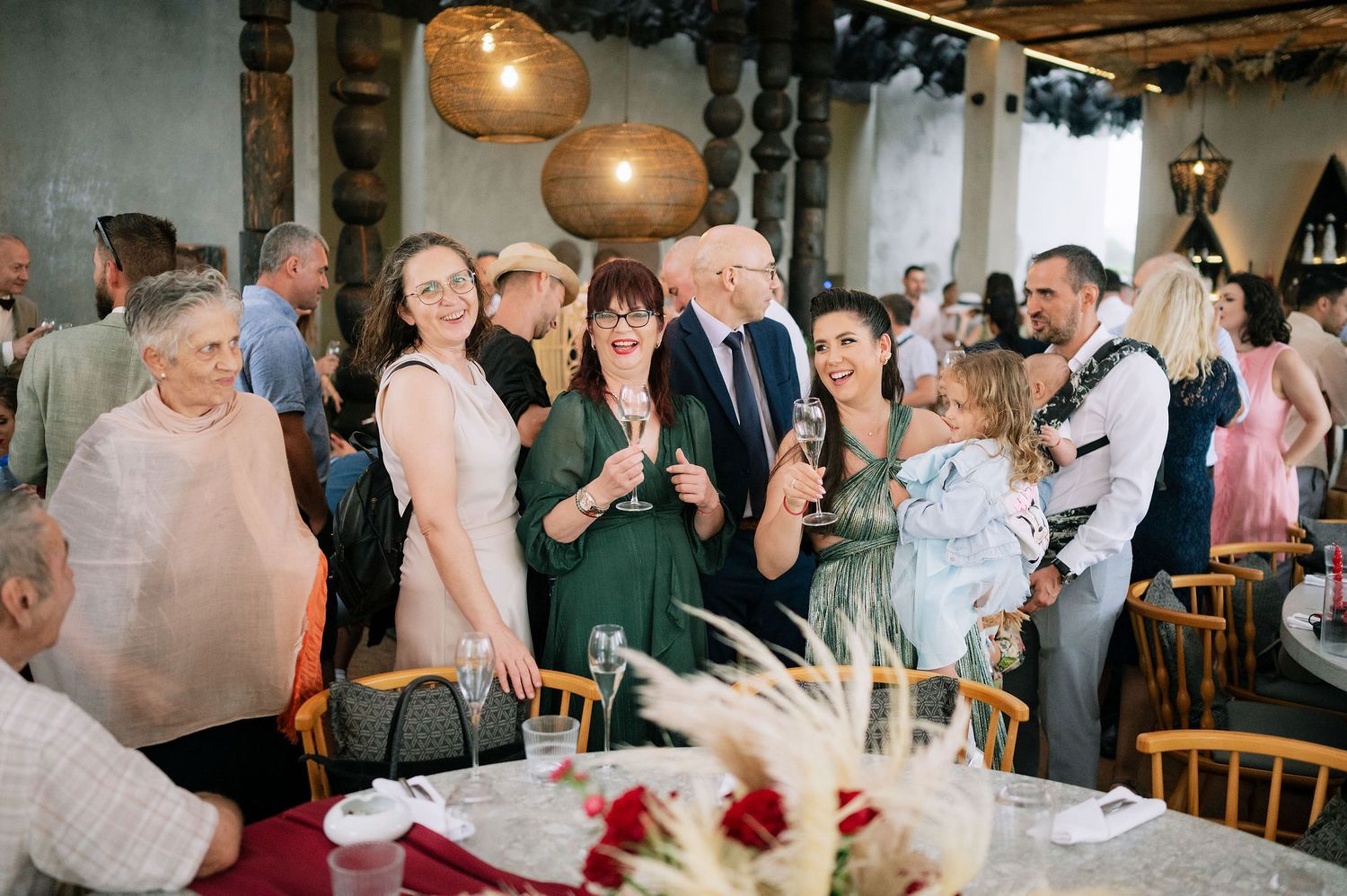 Guests mingling and toasting at decorated tables during an indoor celebration event.