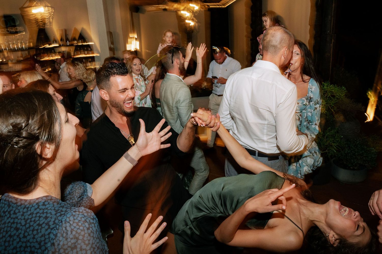 Enthusiastic dancers enjoying themselves at an indoor party with warm lighting.