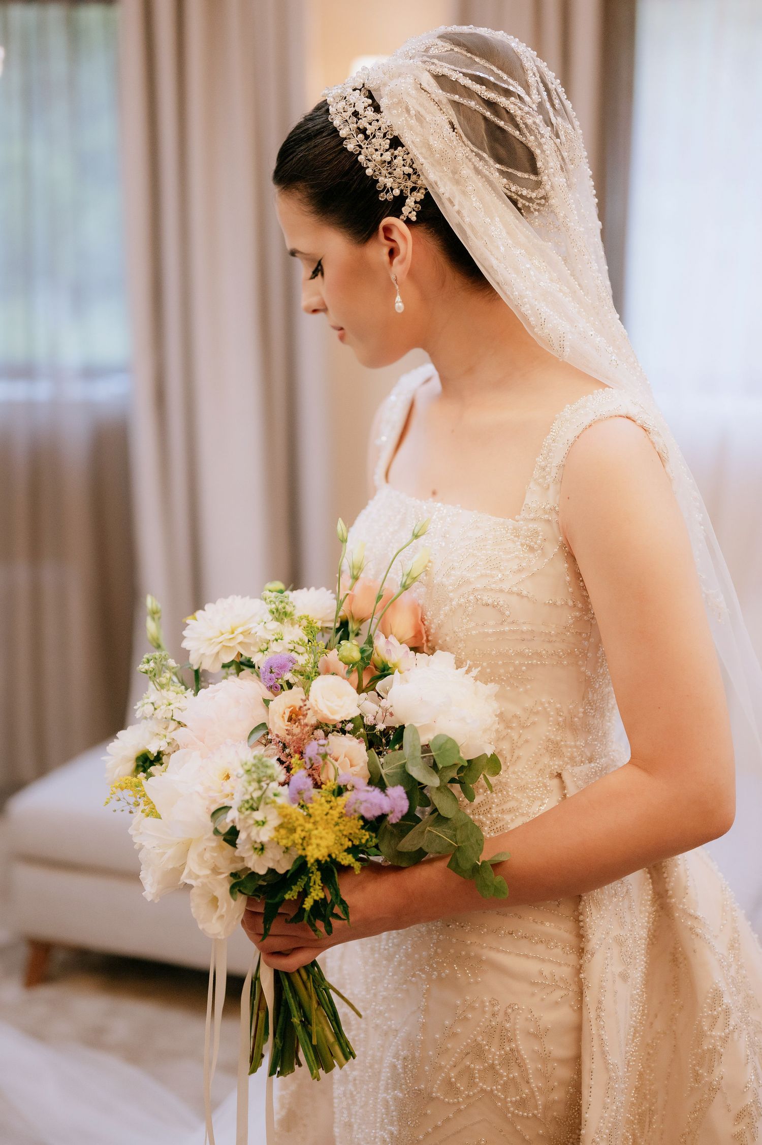 Elegant bridal portrait showcasing detailed lace dress and mixed floral bouquet.