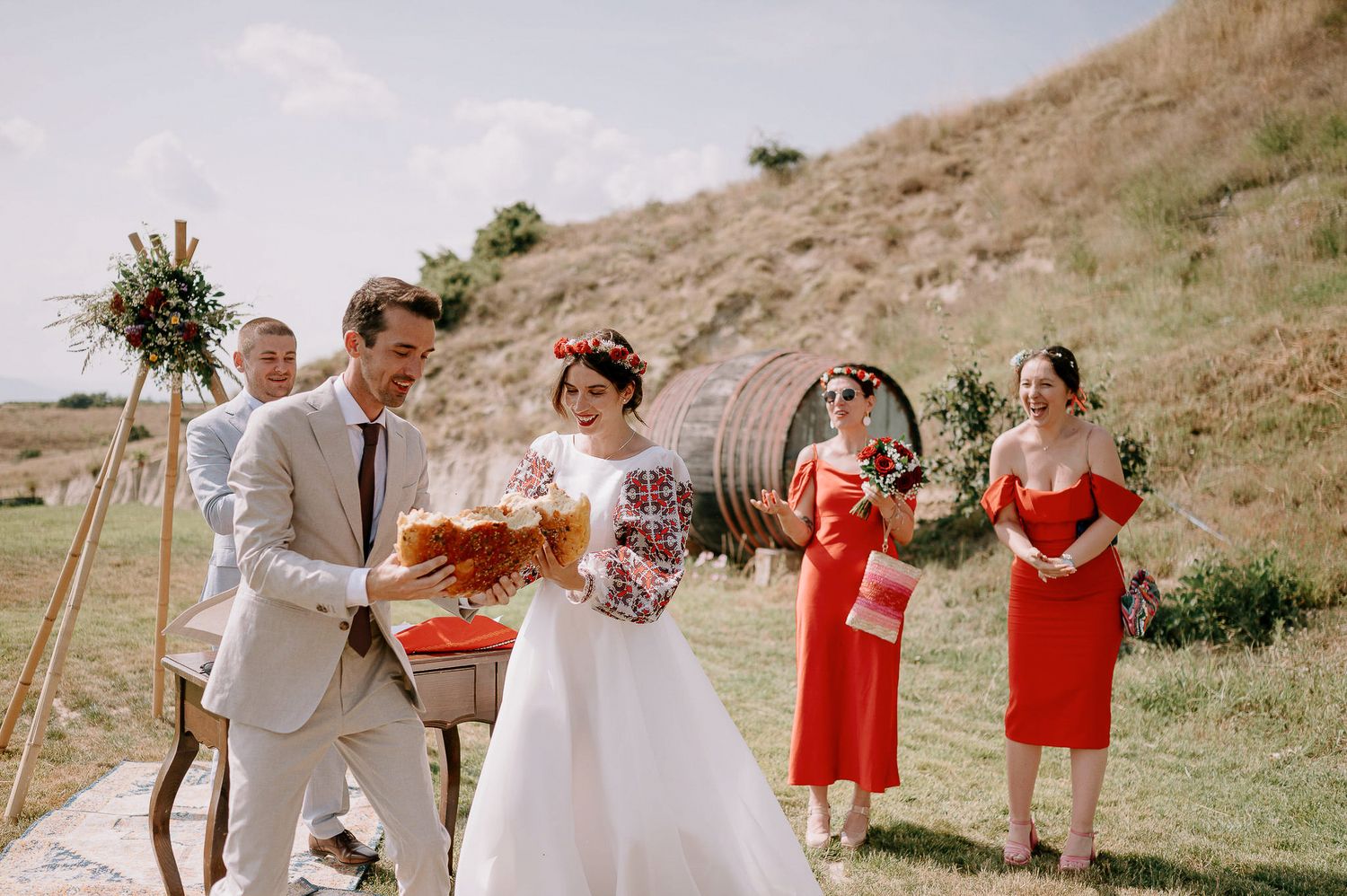 Wedding party poses on scenic hillside with coral and white color scheme.