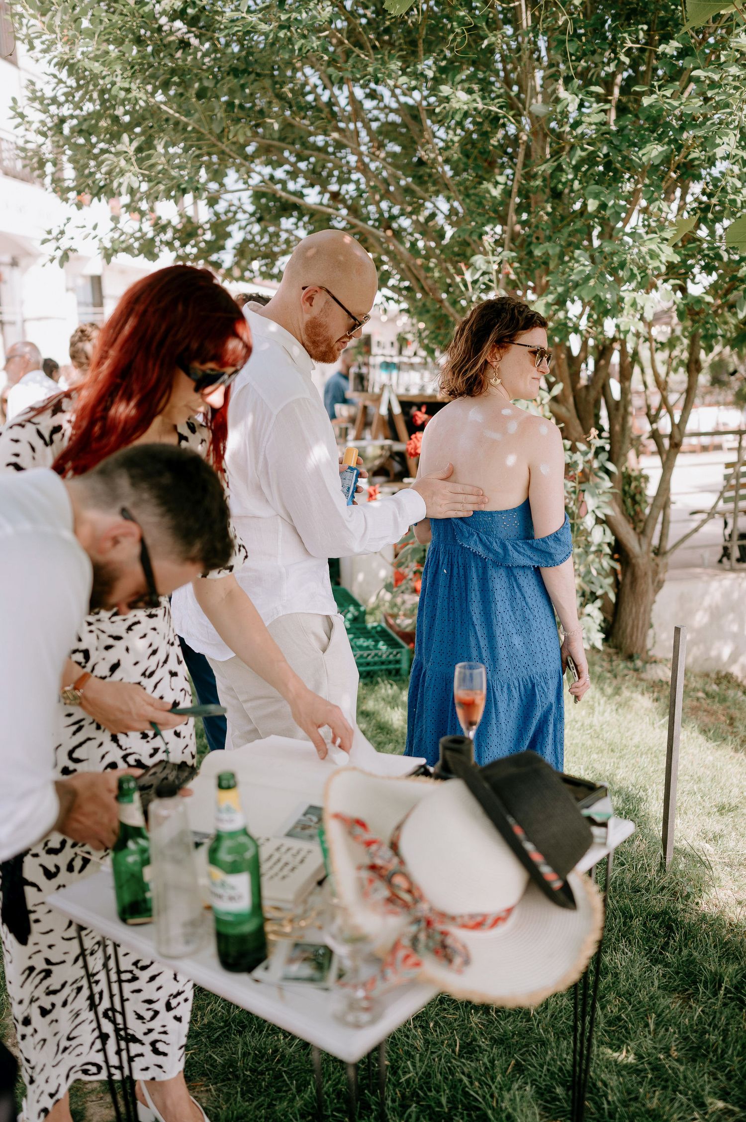 Guests gather around a table with refreshments at an outdoor wedding reception.