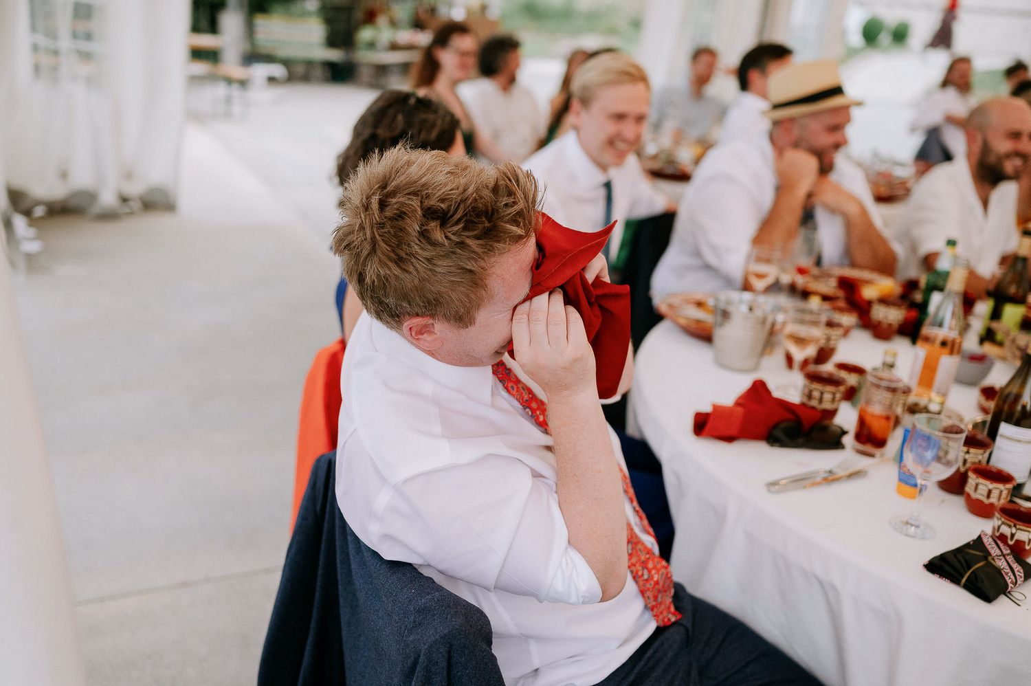 Emotional moment captured during wedding reception speeches with guests seated at decorated tables.