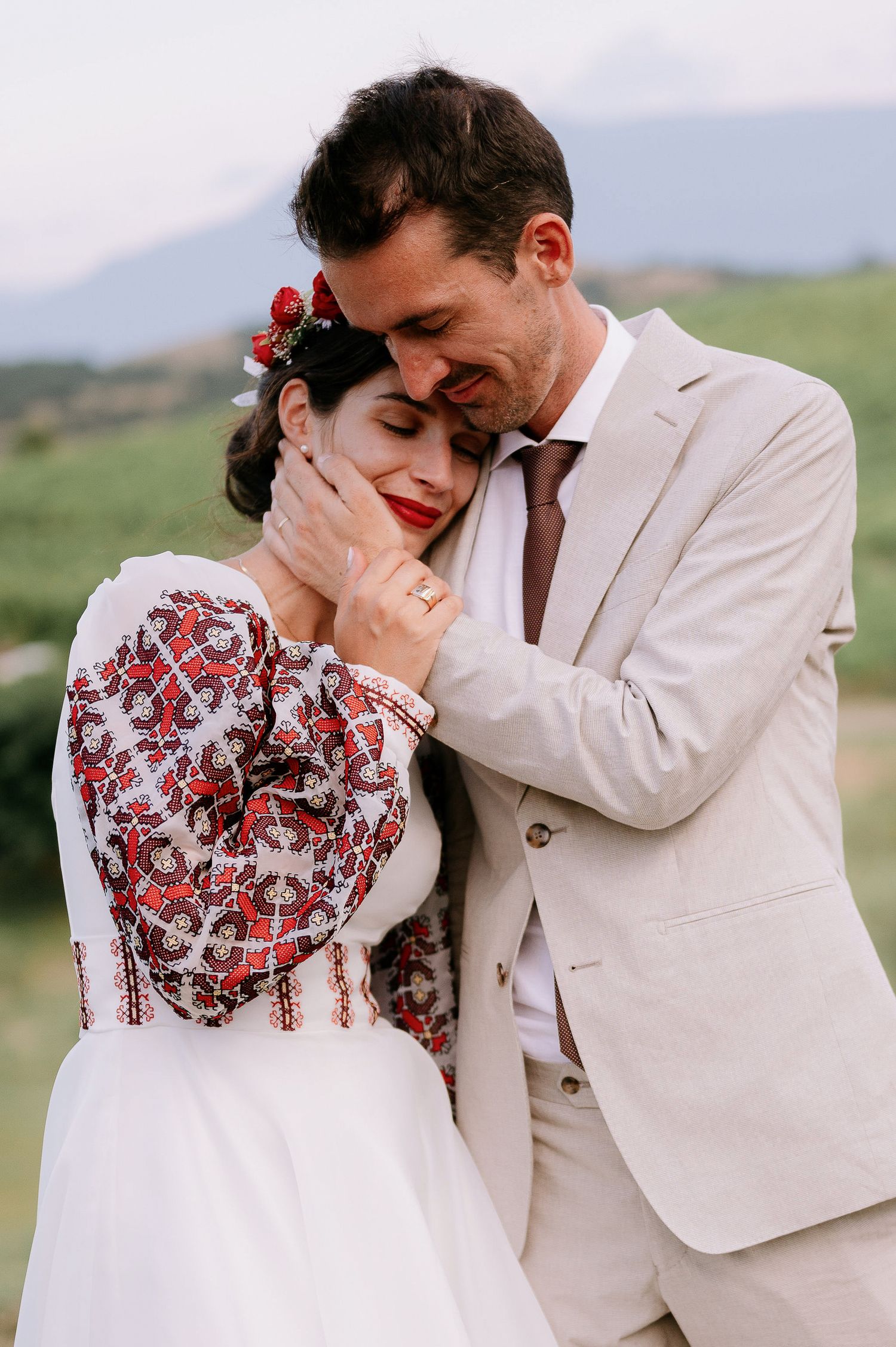 Intimate wedding portrait showing affection between newlyweds in a rustic outdoor setting.